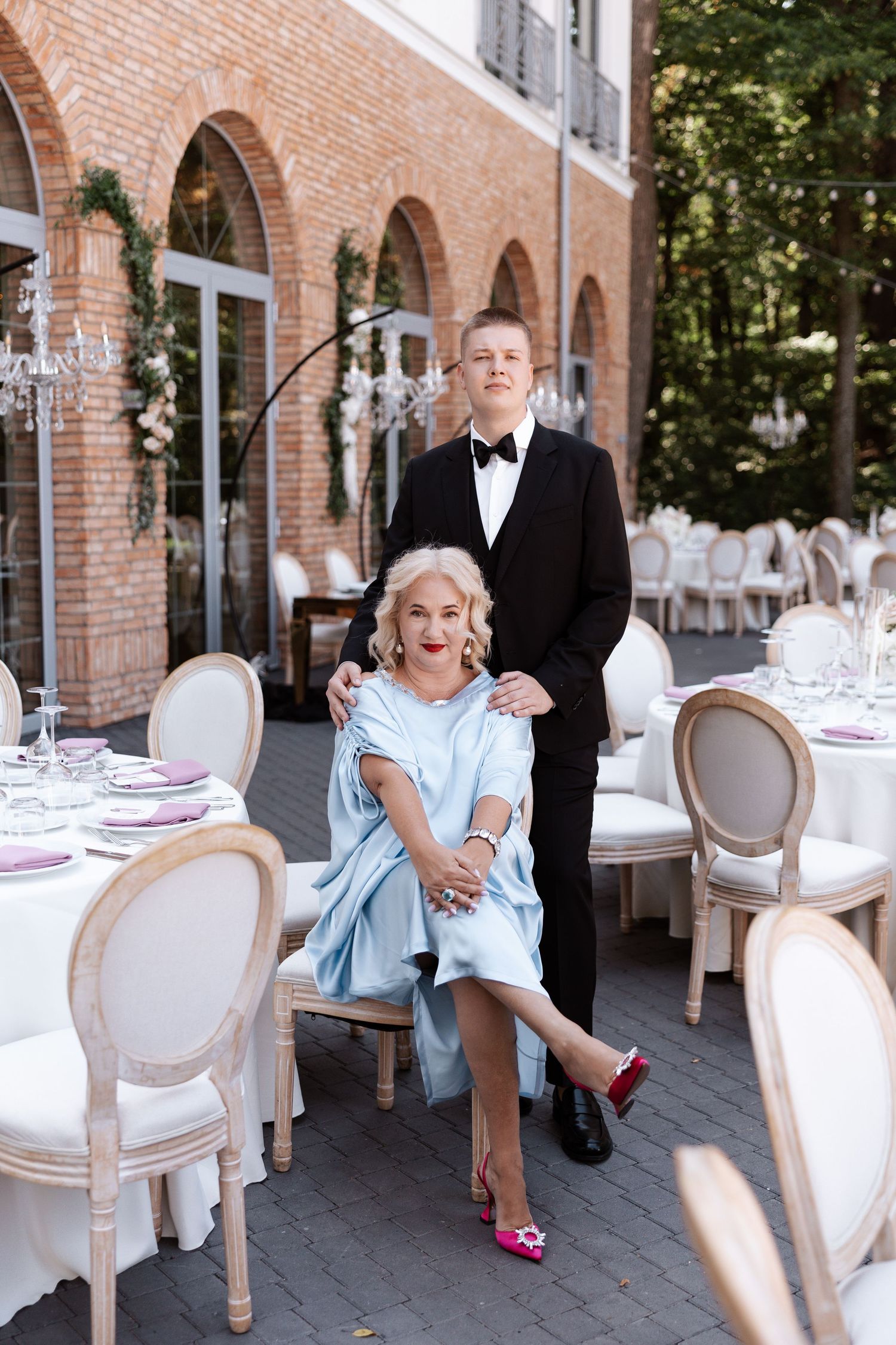 Wedding reception setup with elegant white chairs and tables at a brick arched venue.
