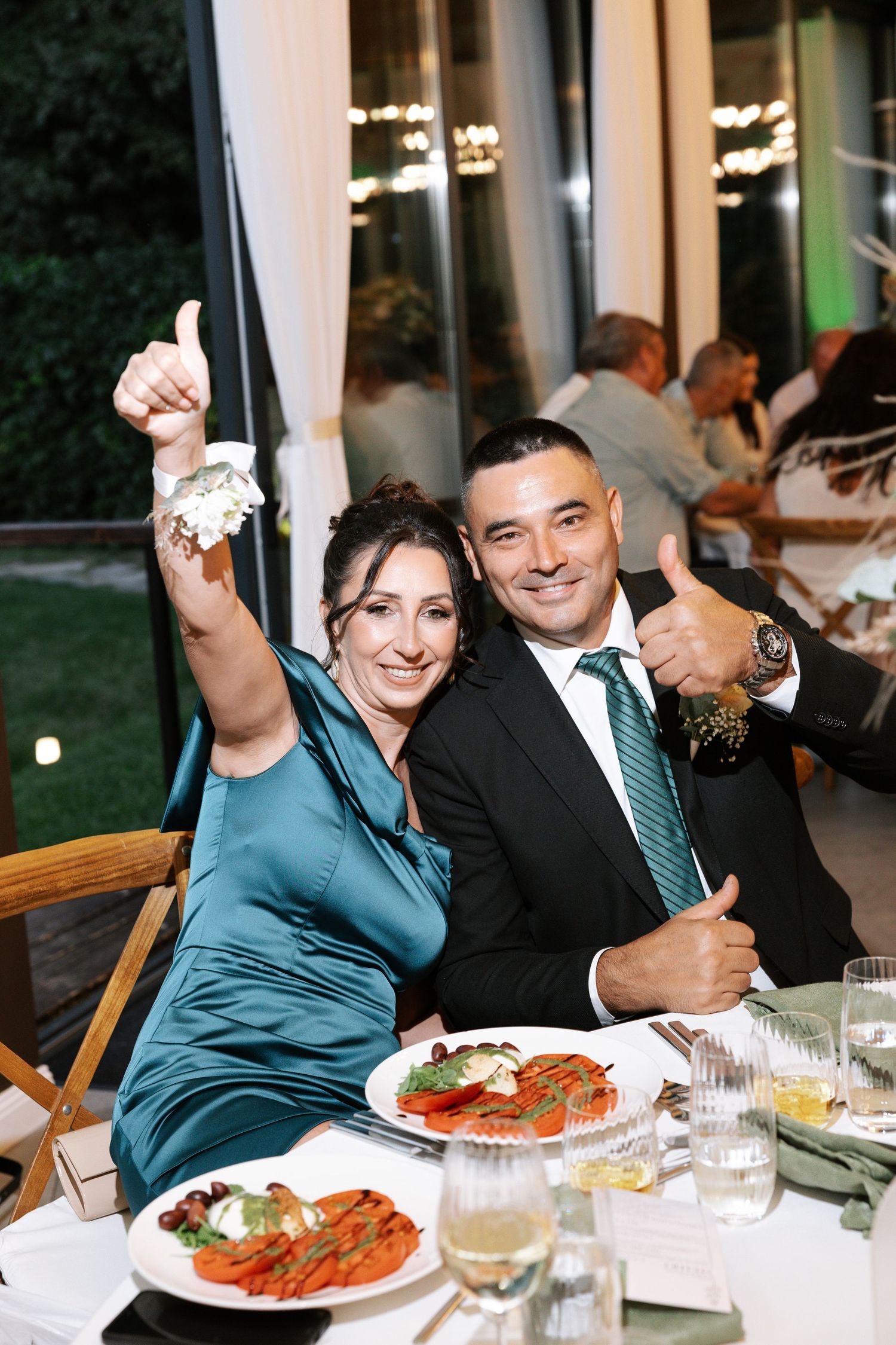 A couple enjoying a meal together at a formal dinner event with plated food and white tablecloths.