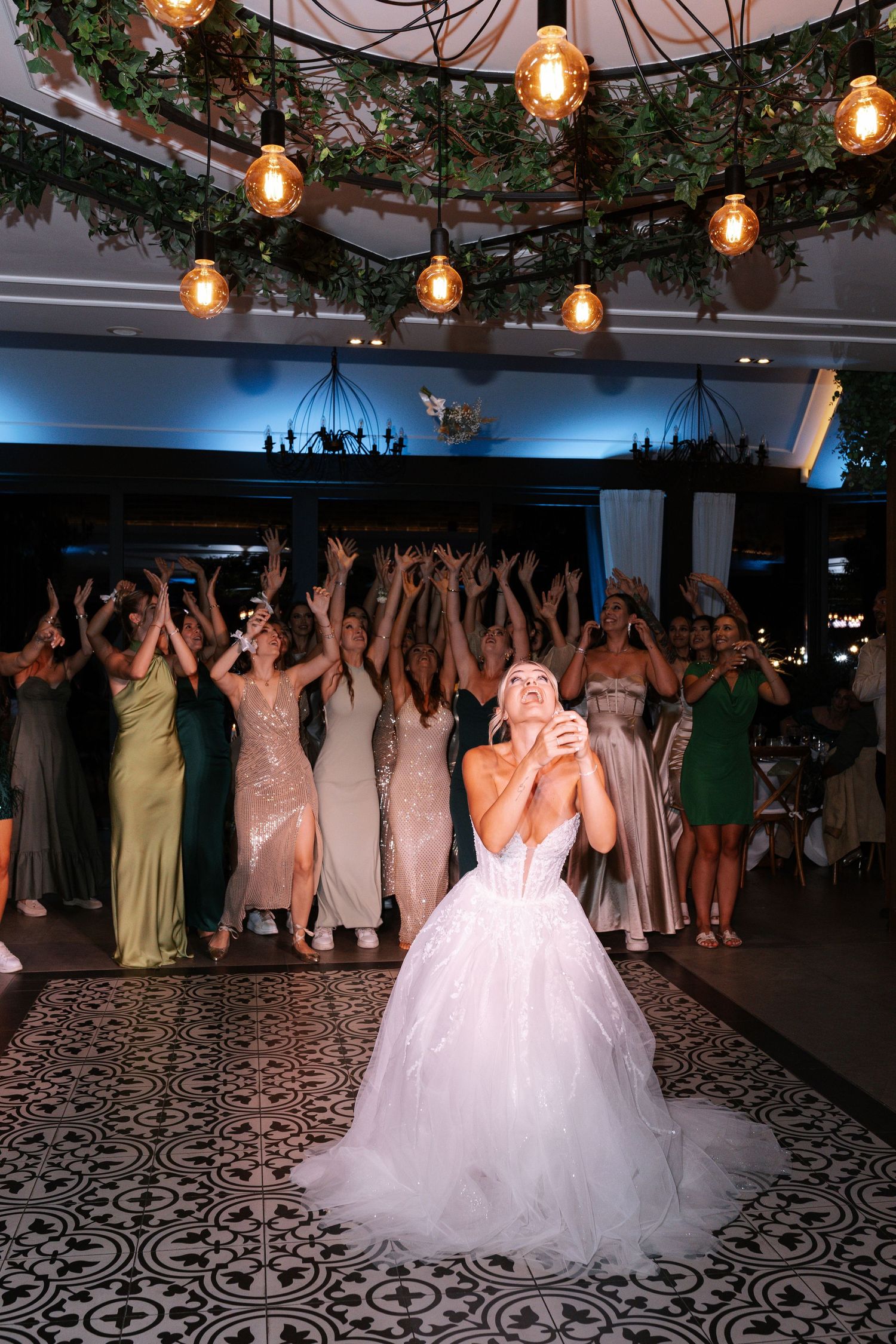 Wedding reception dance floor illuminated by string lights as guests dance and celebrate with the bride in a white gown.