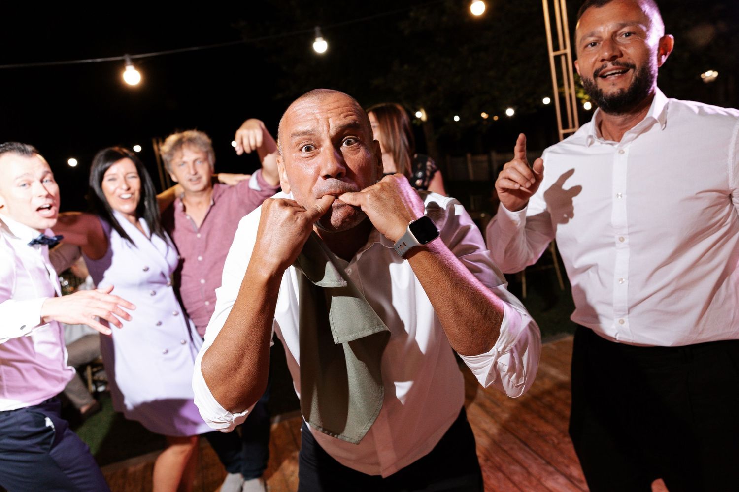 A lively dance party scene with people enjoying themselves on a dance floor under string lights.