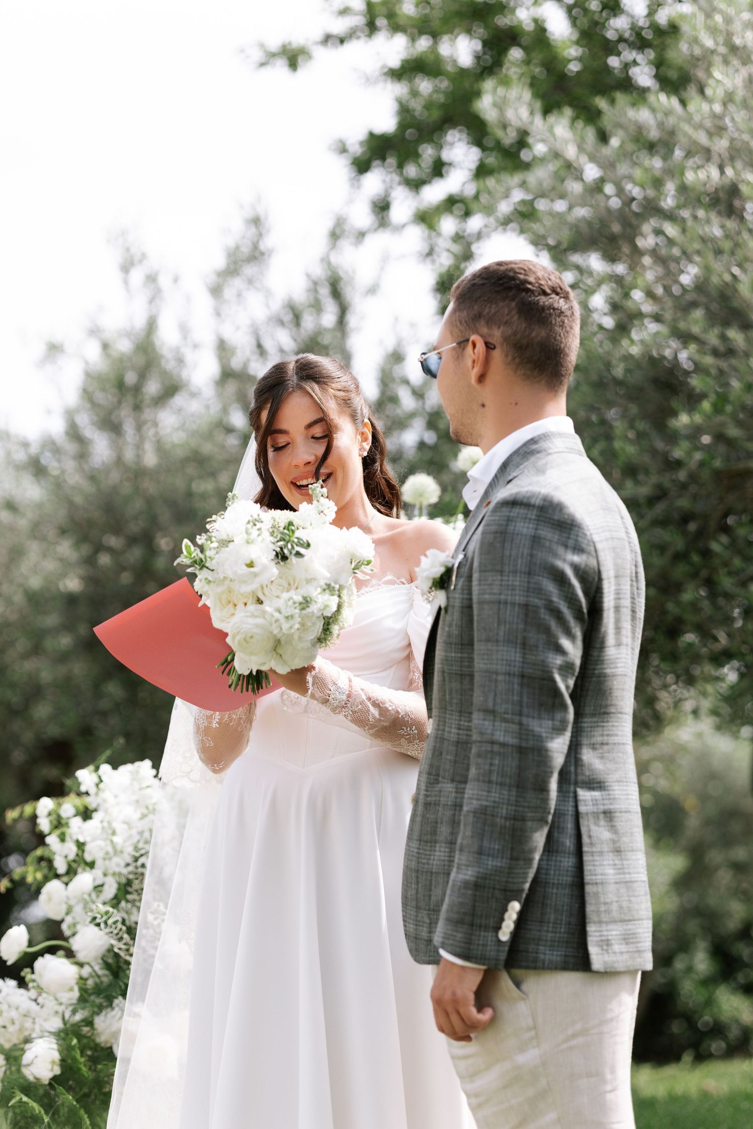 Romantic wedding couple shares tender moments in a garden setting with white floral bouquet and plaid suit.