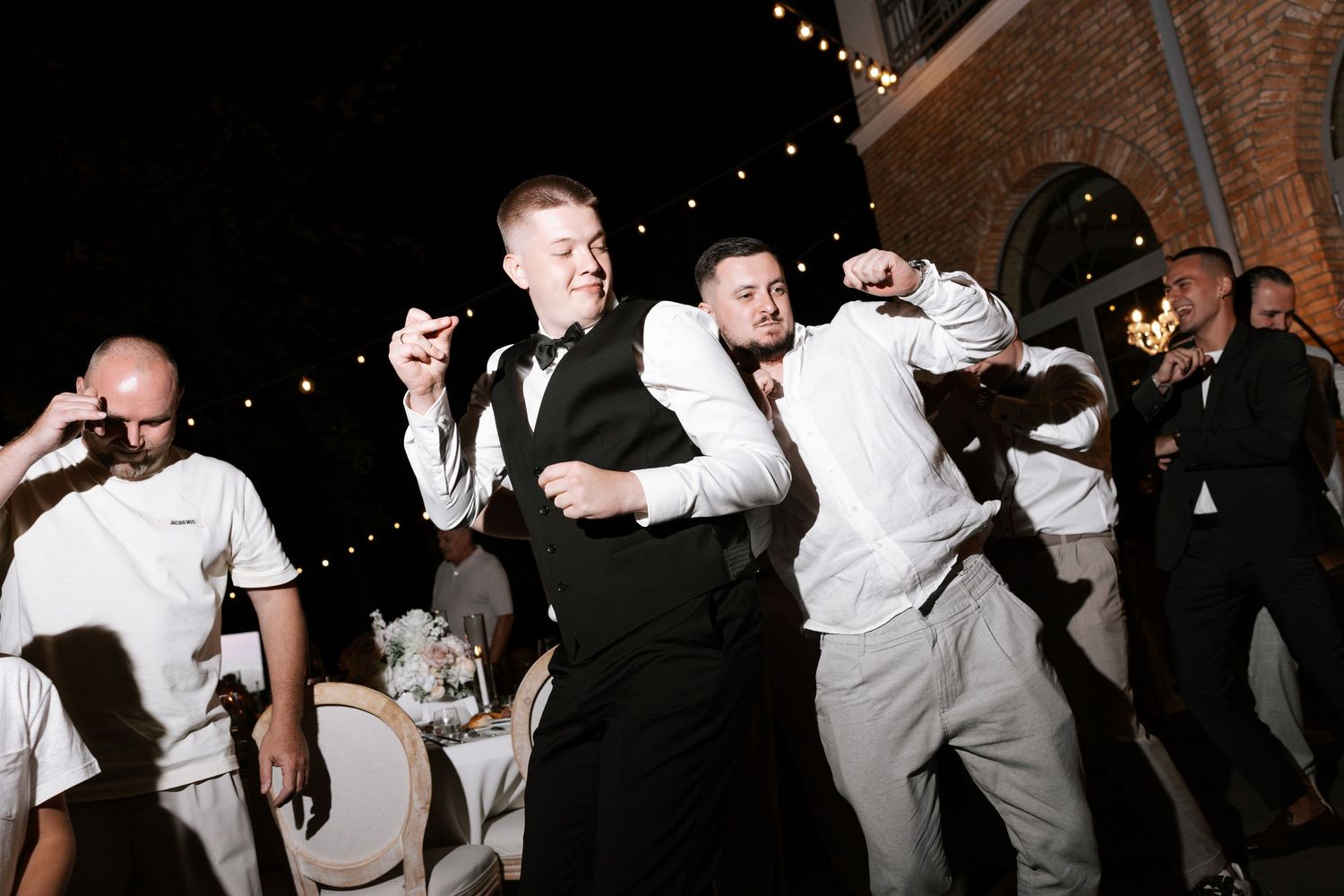 Wedding guests dancing and celebrating at nighttime outdoor reception.