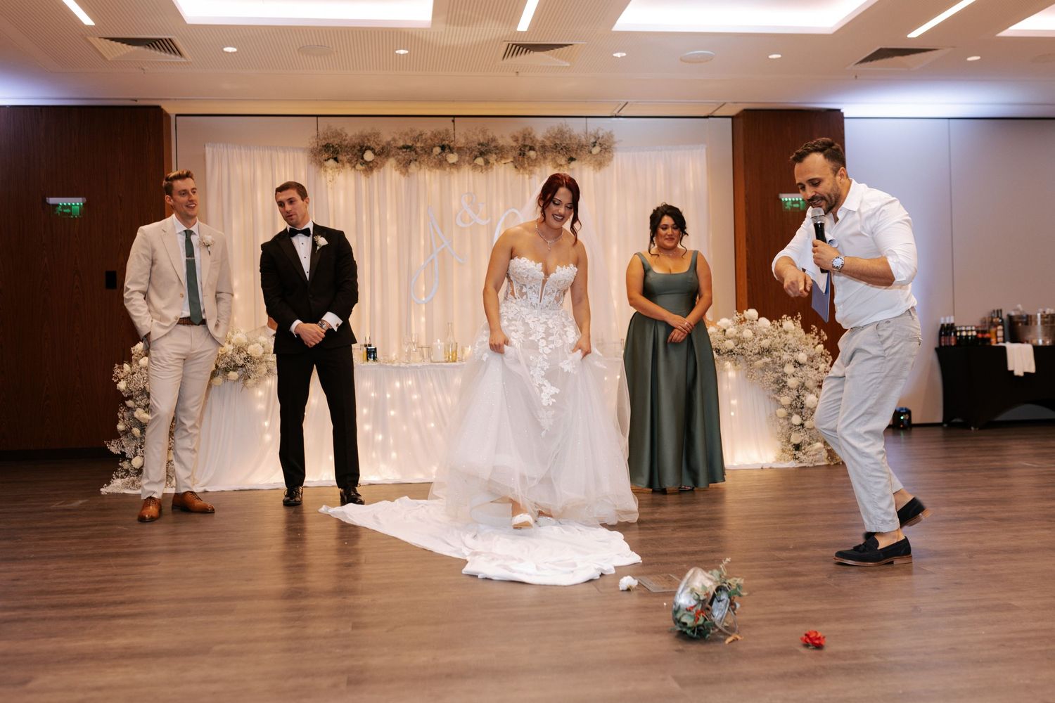 Wedding party playing soccer in an indoor venue with decorative backdrop.