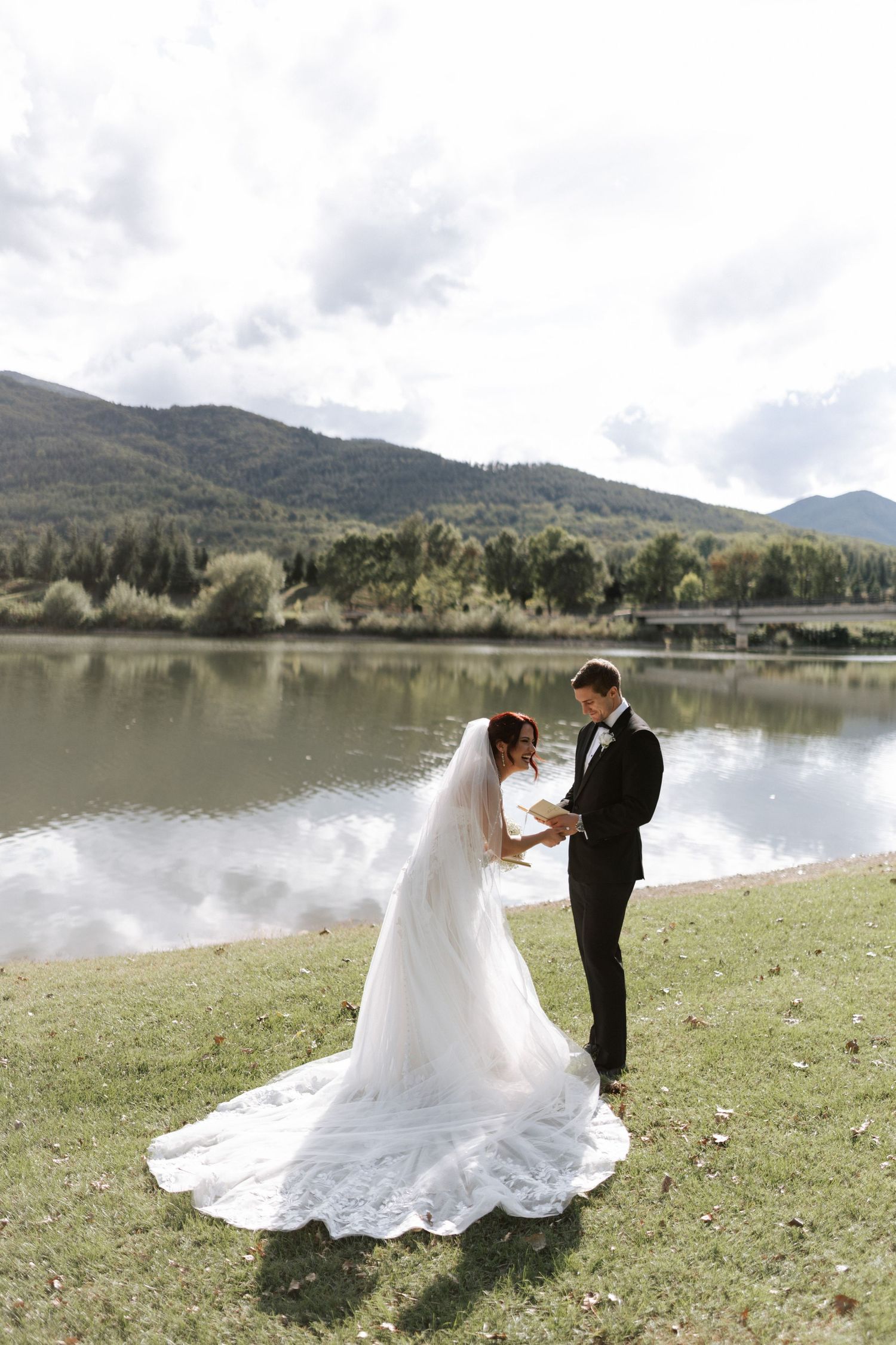 A romantic wedding ceremony unfolds beside a tranquil mountain lake on a beautiful day.