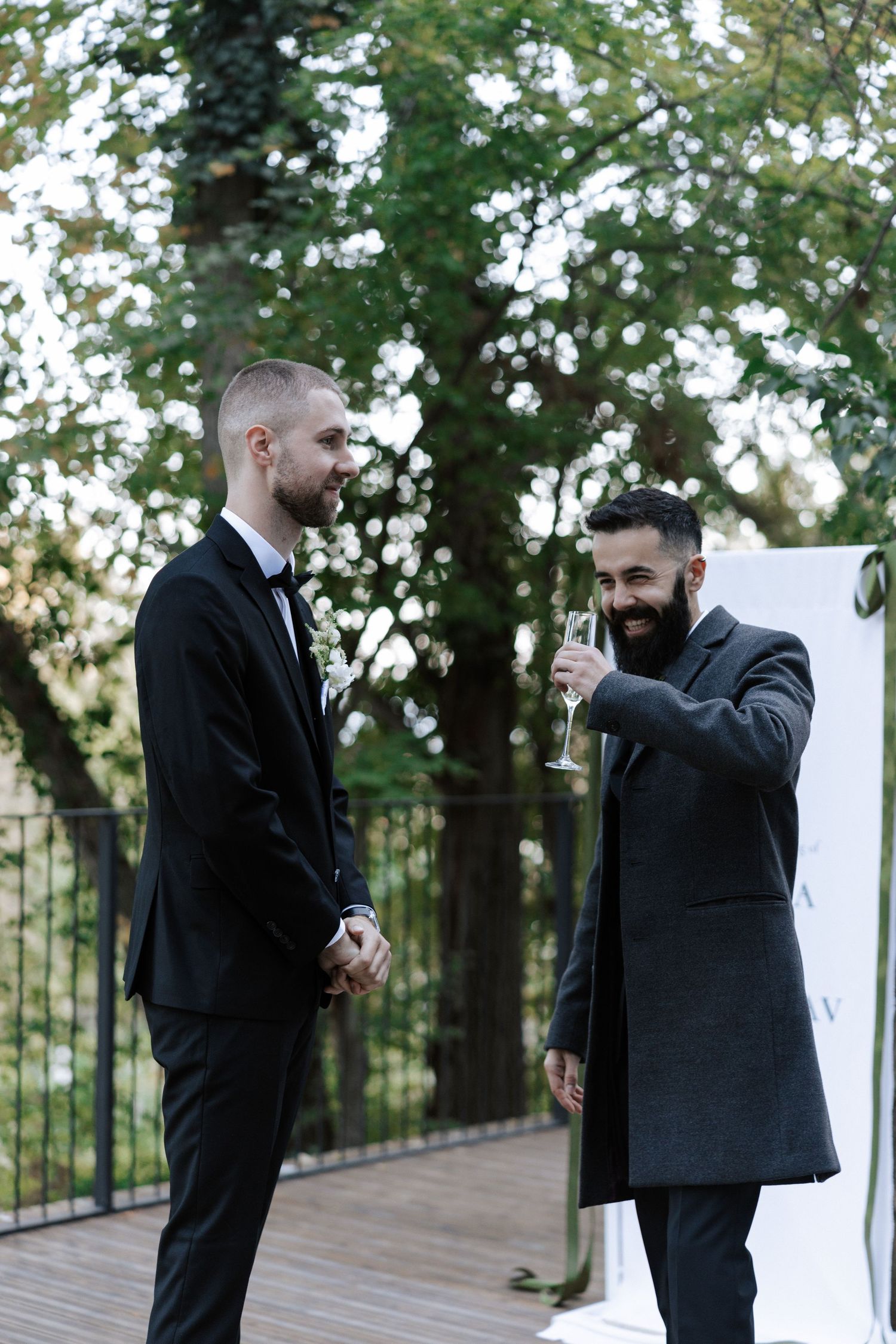 Two guests in formal attire sharing a moment at outdoor wedding venue.