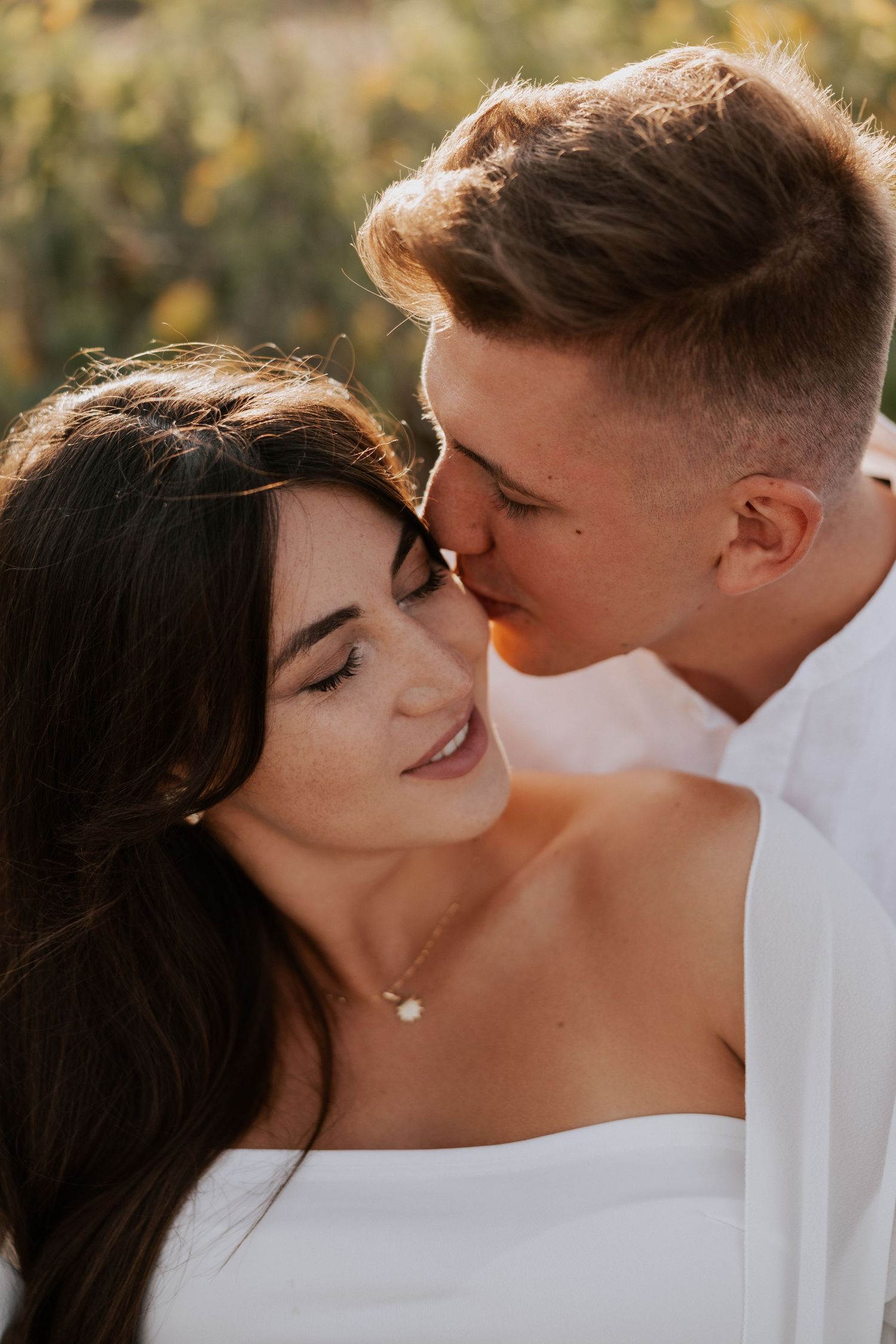 Intimate close-up portrait of couple sharing tender moment in golden light.