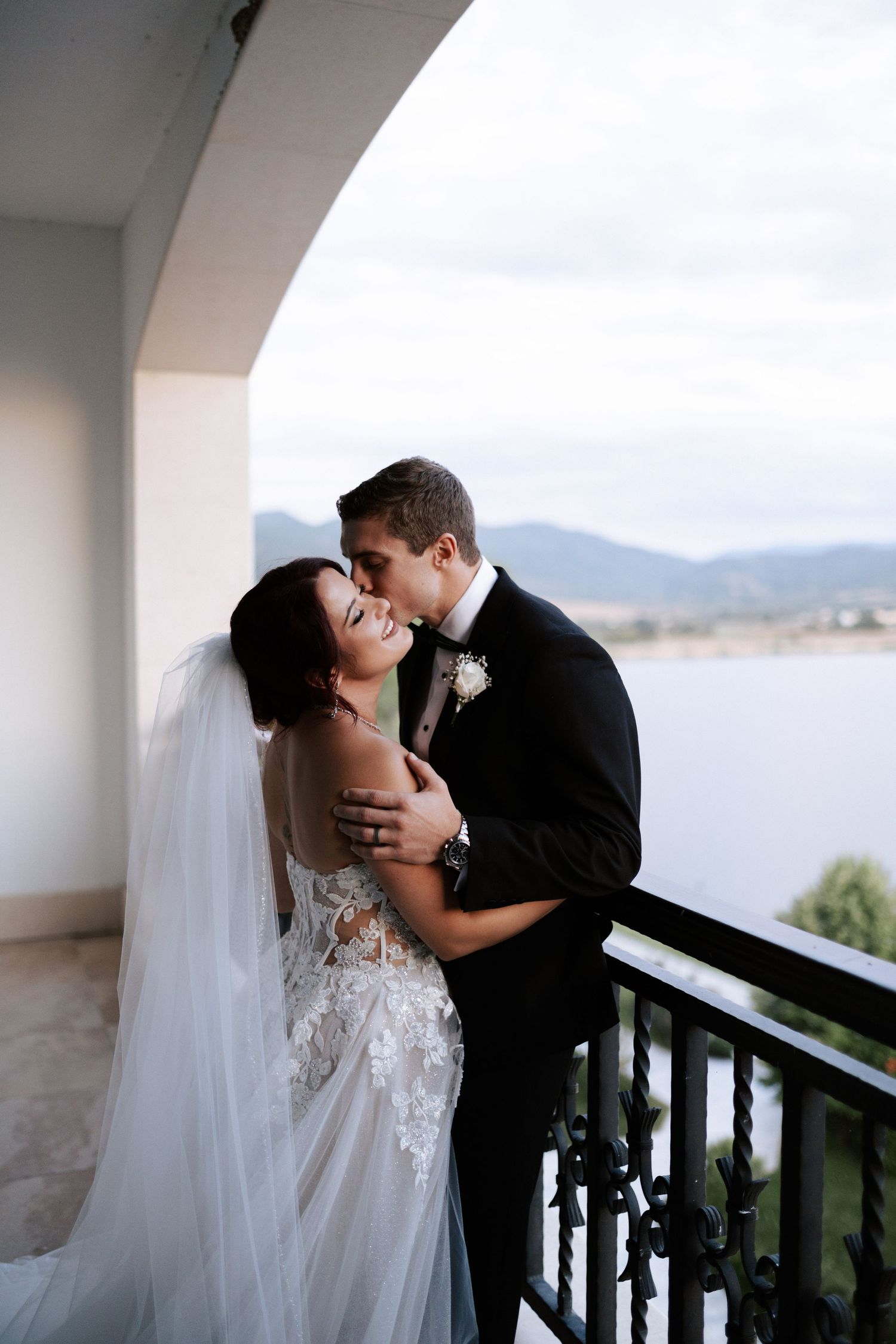 Romantic balcony moment with mountain views during wedding celebration.