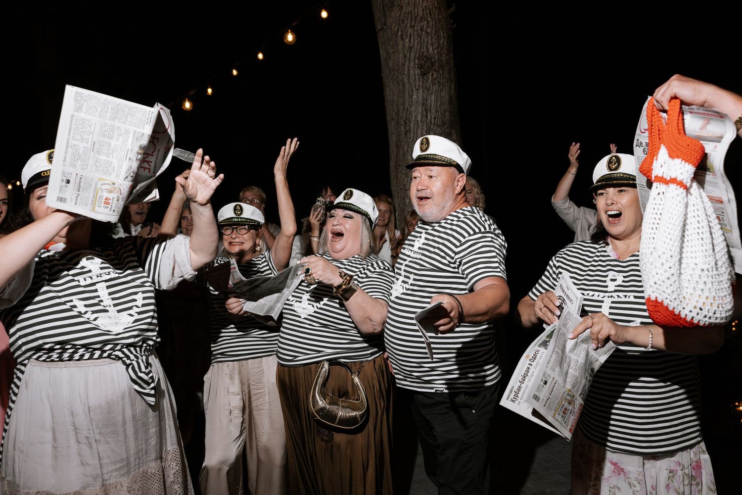 Wedding guests in striped shirts performing choreographed dance moves at night.
