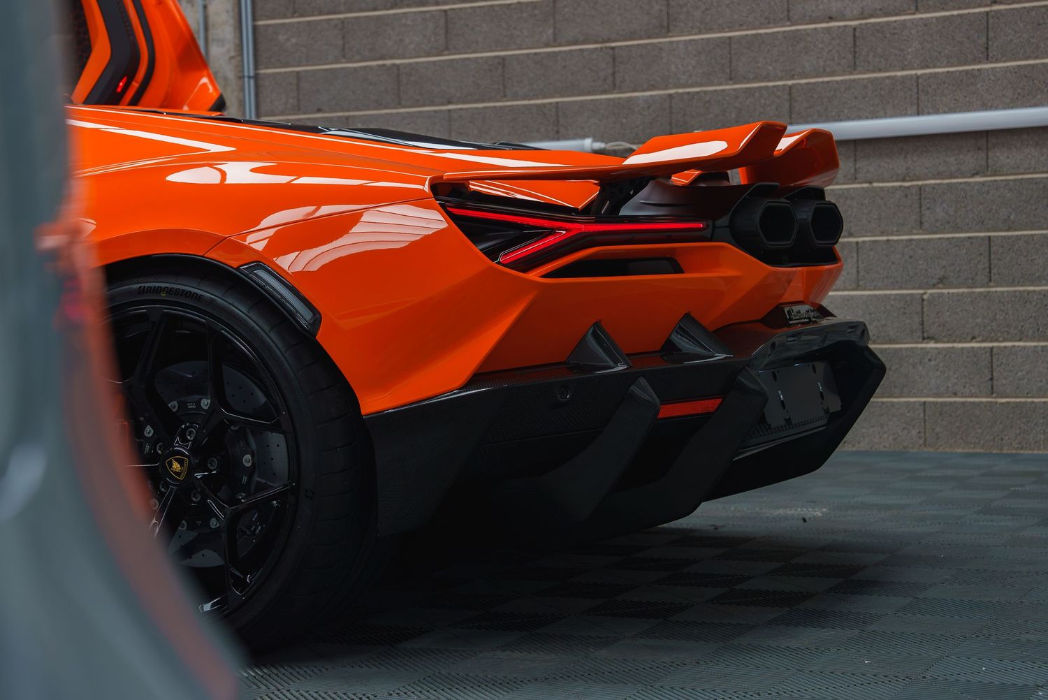 Rear view of an orange McLaren sports car showing aerodynamic diffuser and design details.