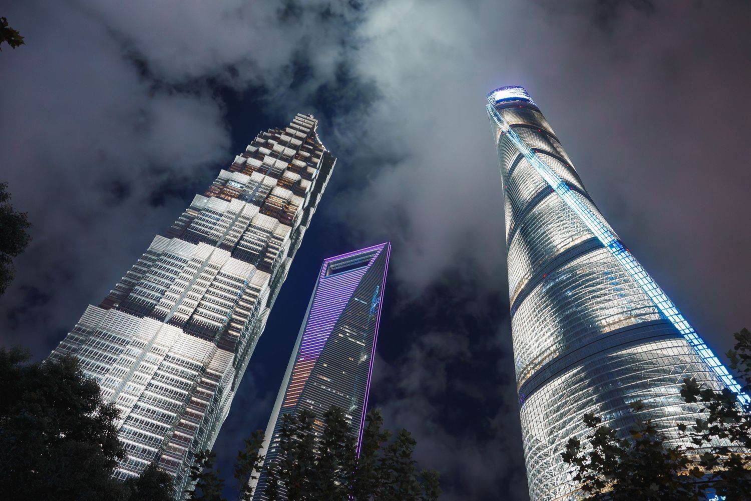 Modern skyscraper with curved architecture photographed against cloudy dramatic sky.