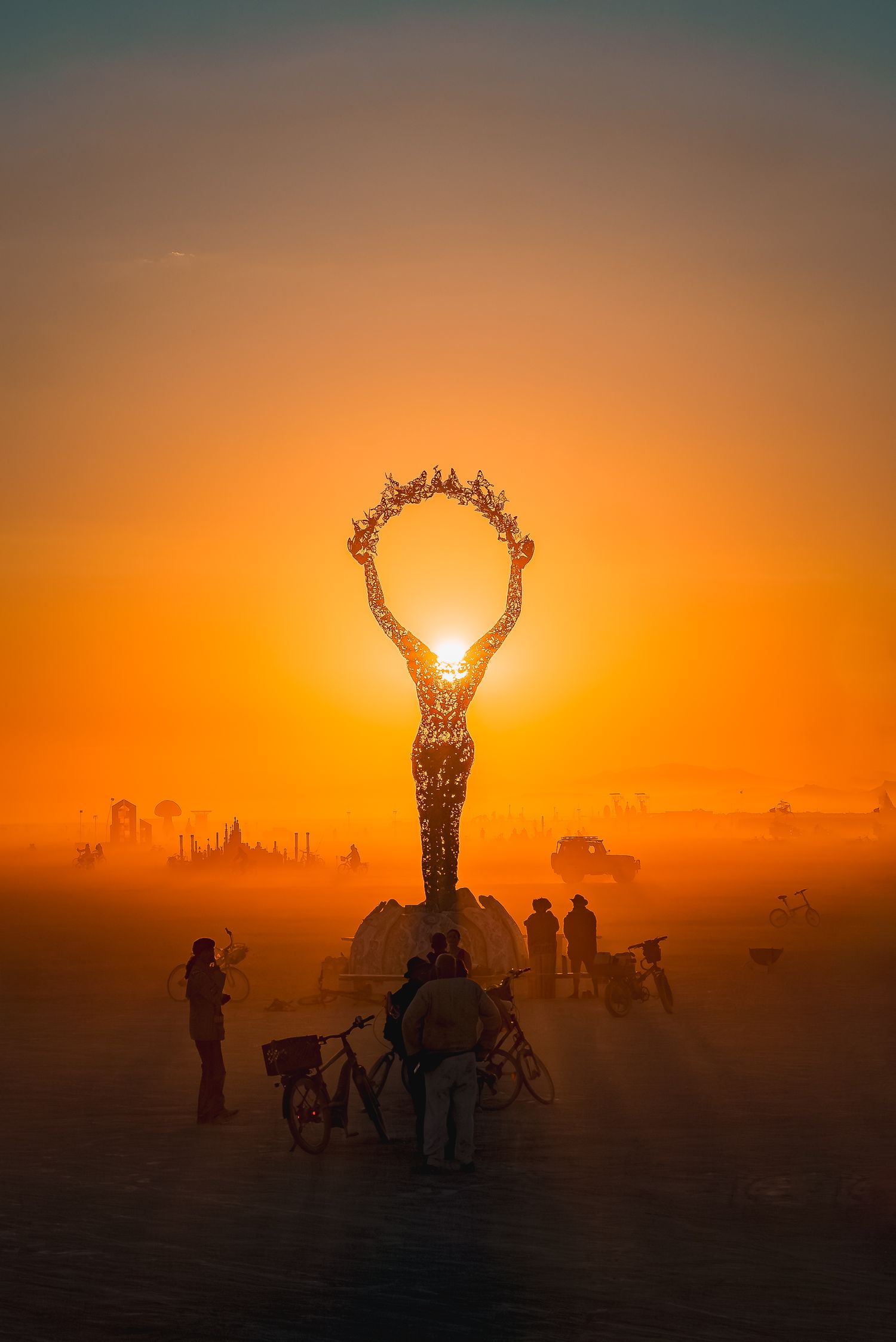 Silhouettes of festival-goers against a dramatic orange desert sunset at Burning Man.