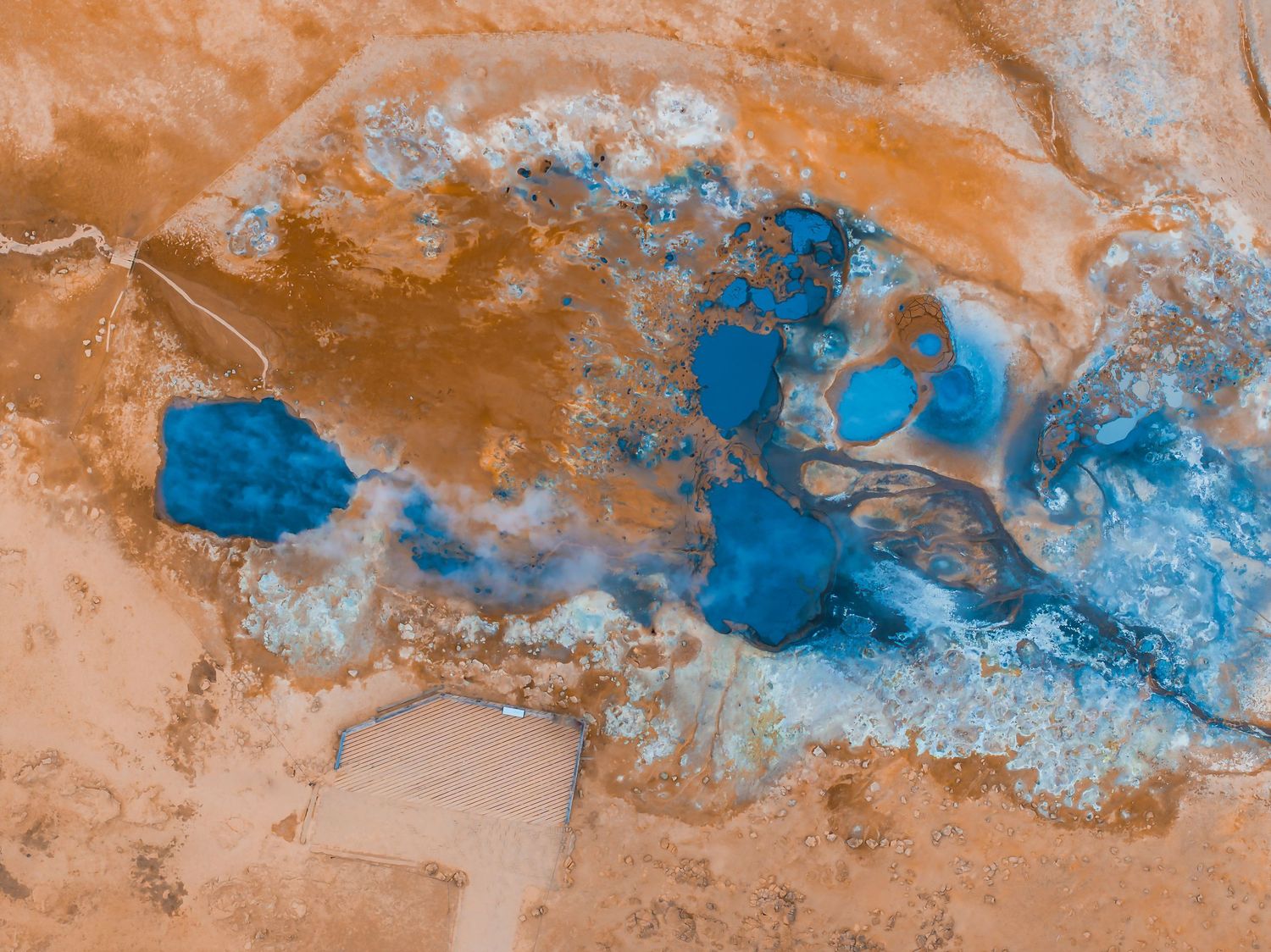 Abstract aerial view of bright blue lakes contrasting with orange desert terrain.