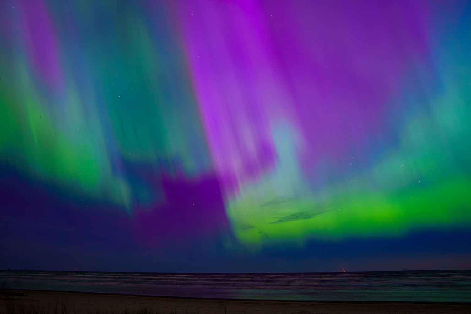 Northern lights display vibrant purple and green colors across the night sky horizon.