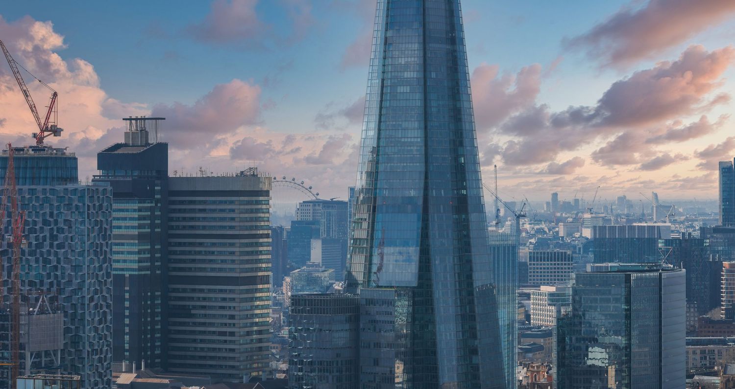 Modern glass skyscrapers of London's business district against dramatic evening sky.