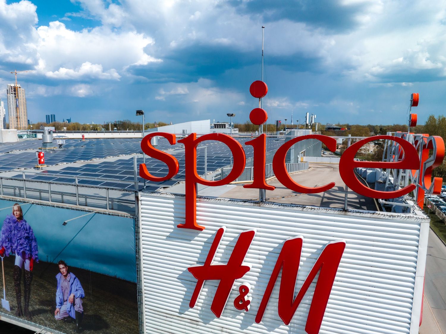 Red Spice and H&M signage on a retail building exterior with blue sky and clouds.