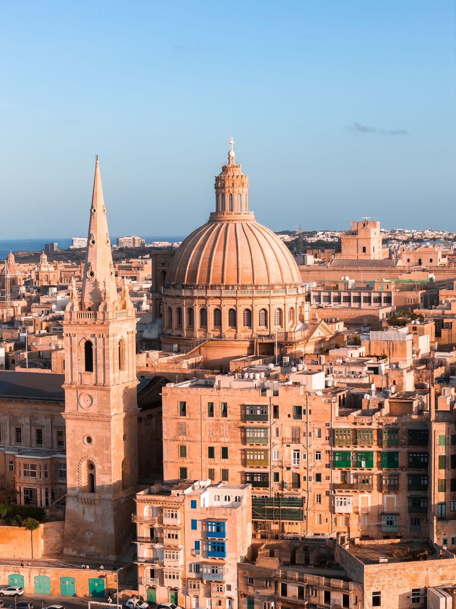 Historic skyline of Valletta, Malta with ornate church domes and traditional limestone architecture glowing in warm sunlight.