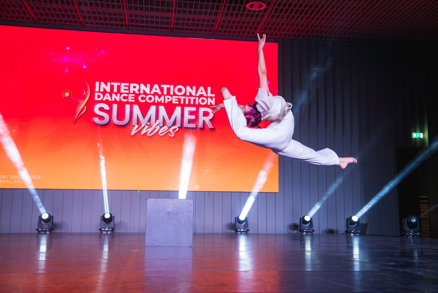 Stage performance with dramatic lighting and dancers creating dynamic movements.