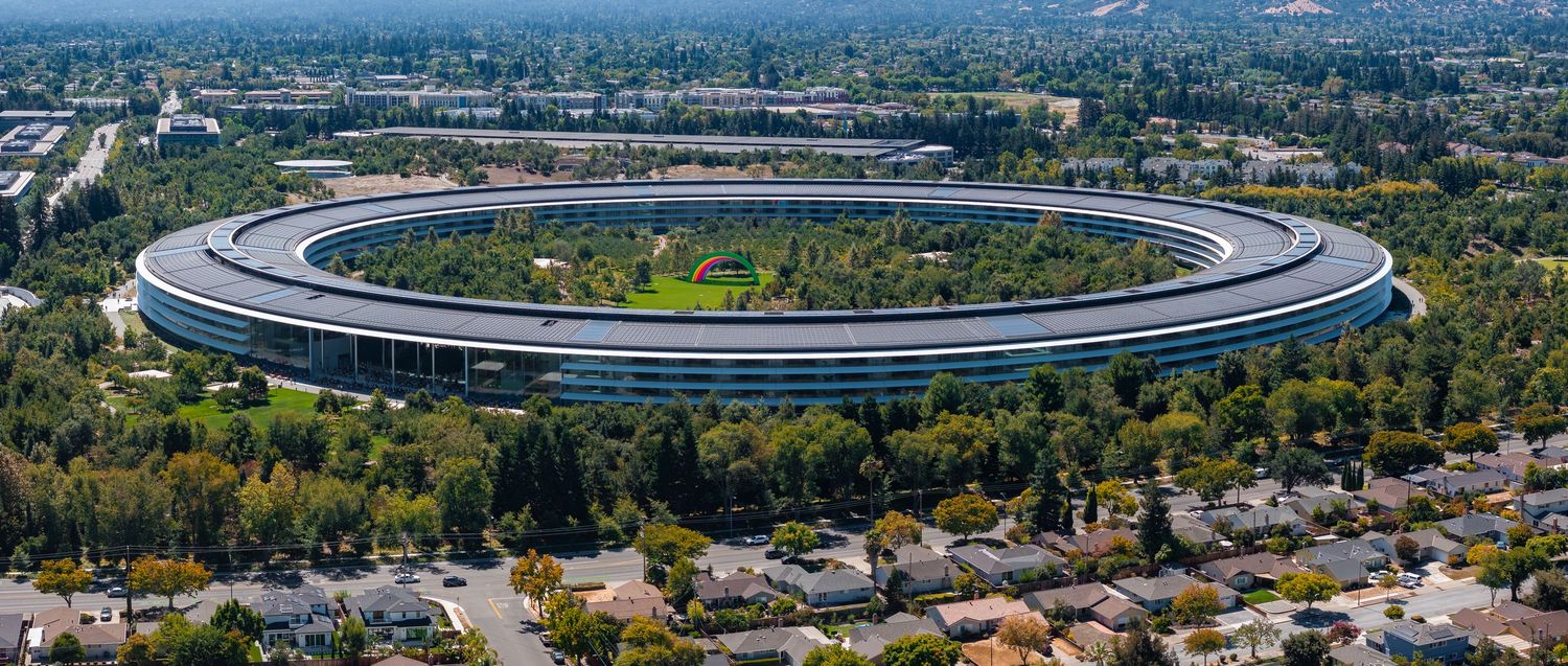 Aerial panorama of Apple Park's circular campus headquarters surrounded by greenery in Cupertino.