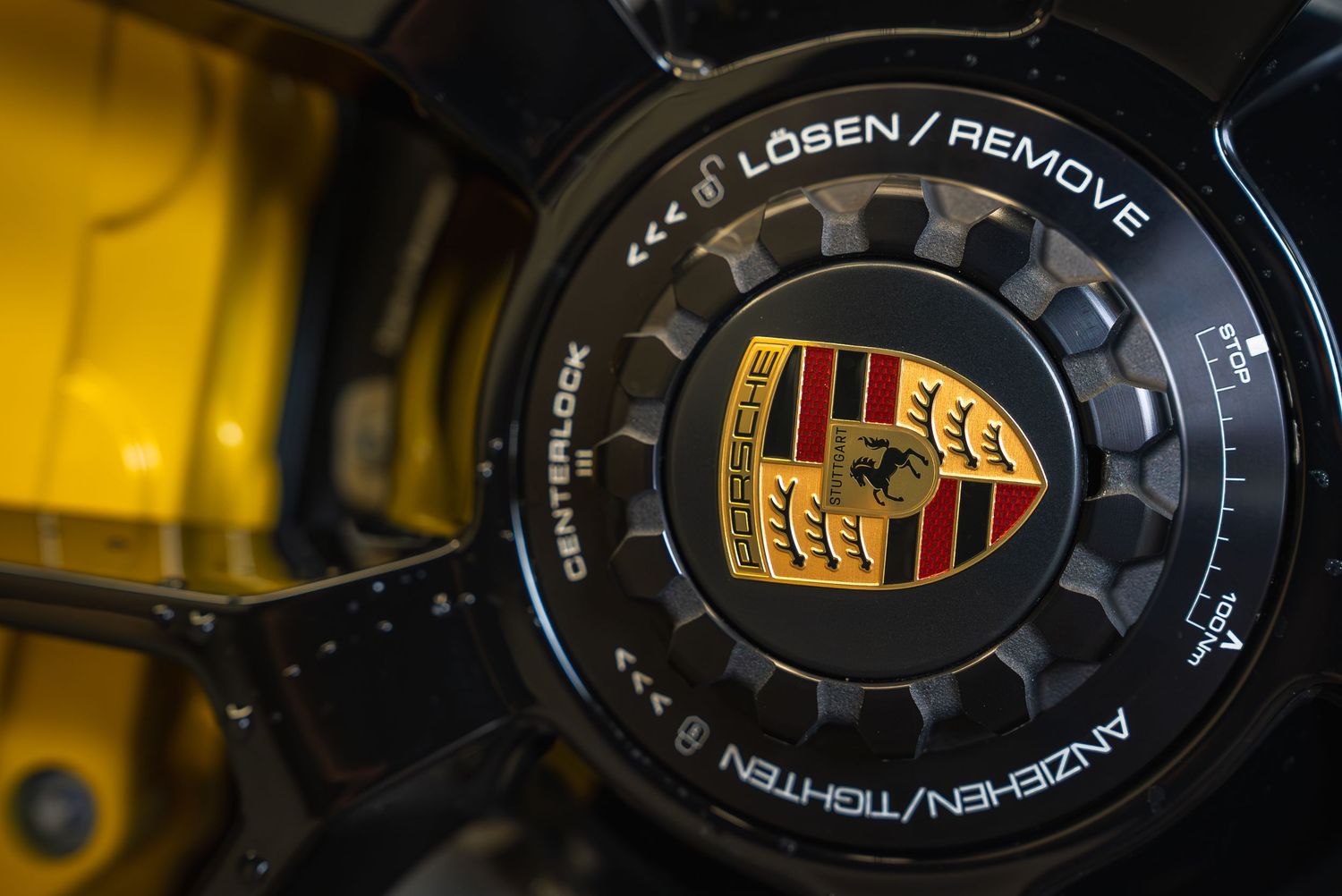 Close-up detail of Porsche wheel center caps and emblems with gold accents.