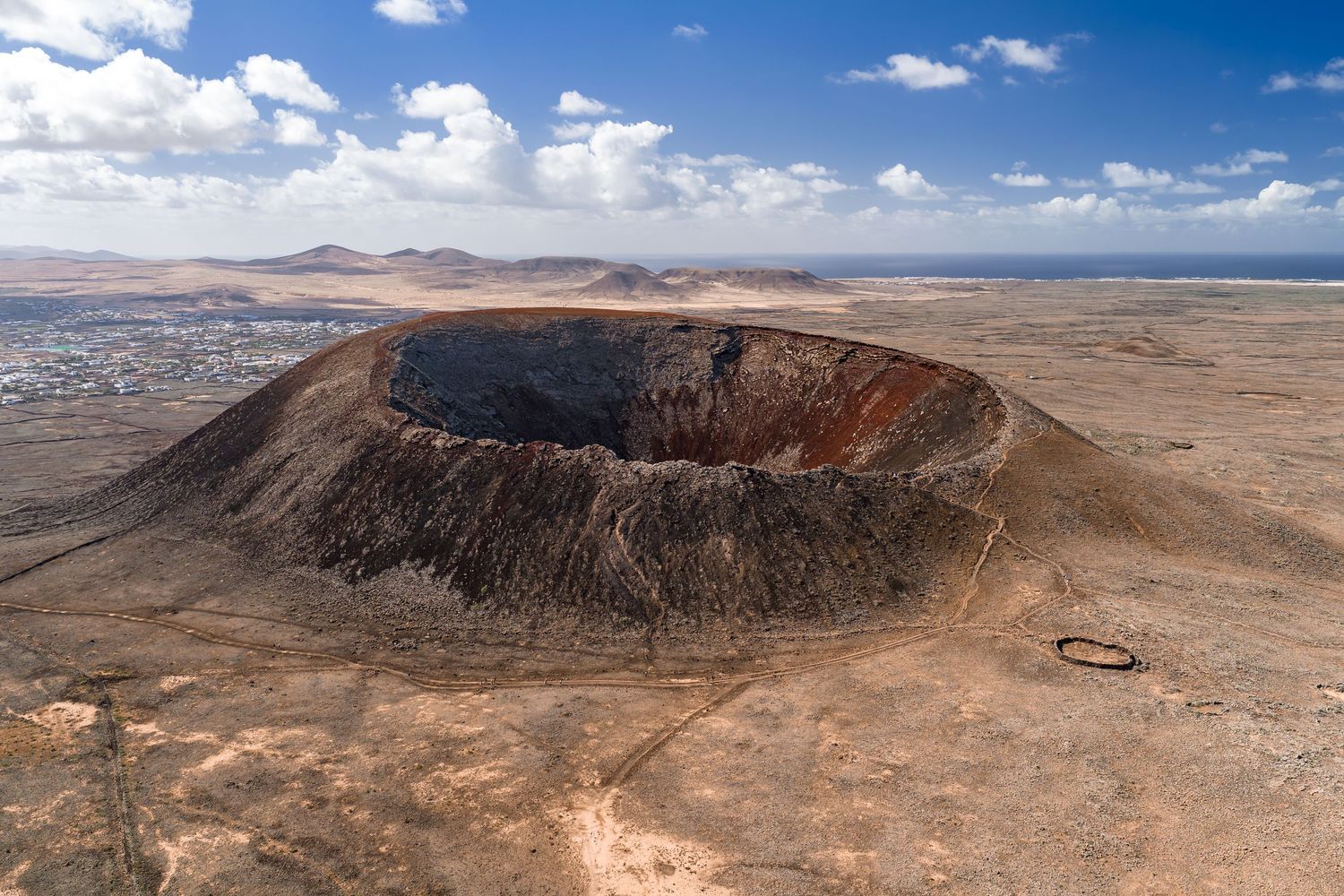 A series of aerial views showing a desert crater formation with rocky terrain and blue skies in the background.
