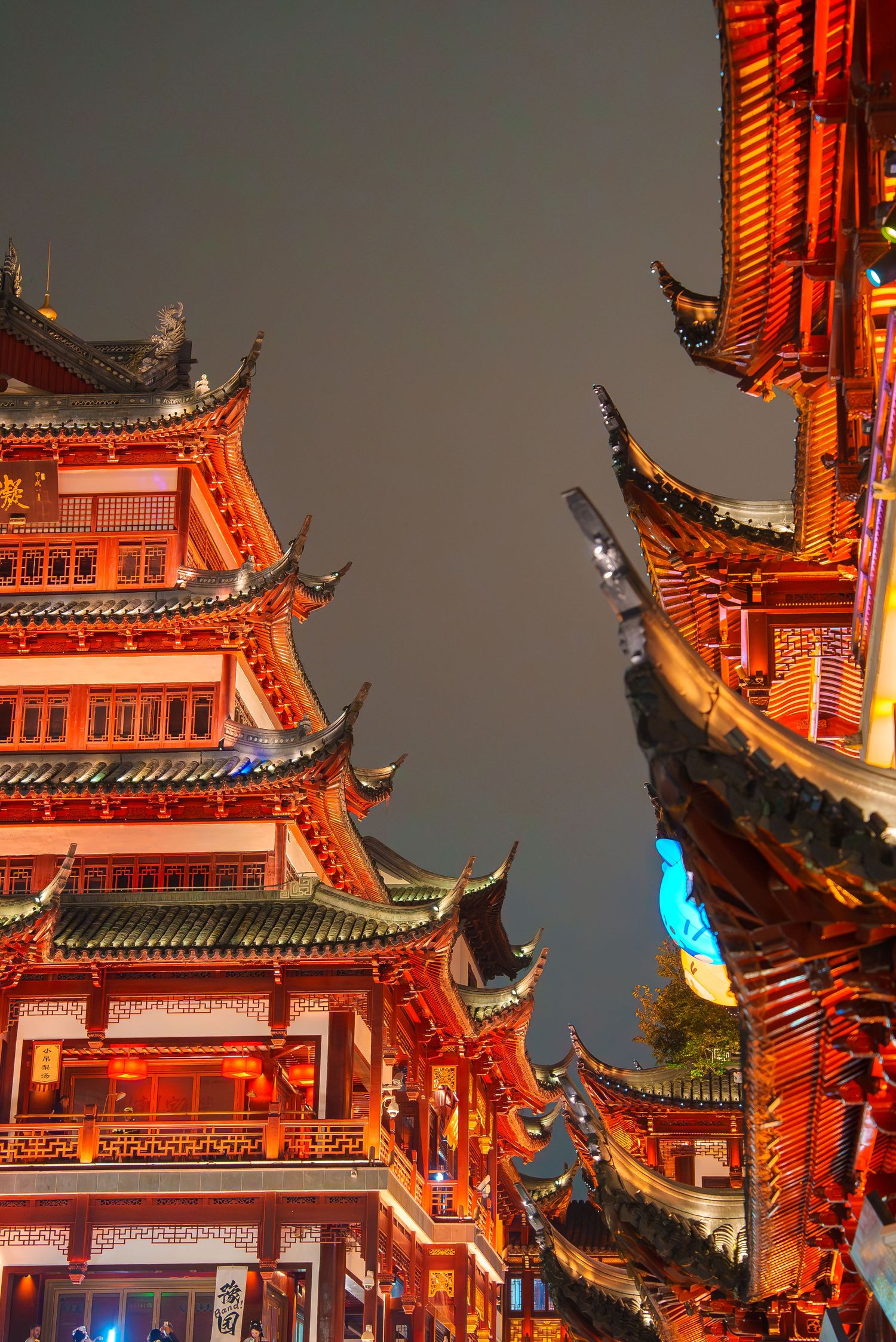 Traditional Chinese architecture with illuminated red pagodas and ornate rooflines at night.