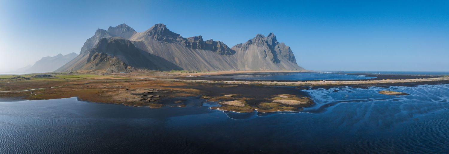 Panoramic coastal landscape with dramatic mountain range and black sand beaches in Iceland.