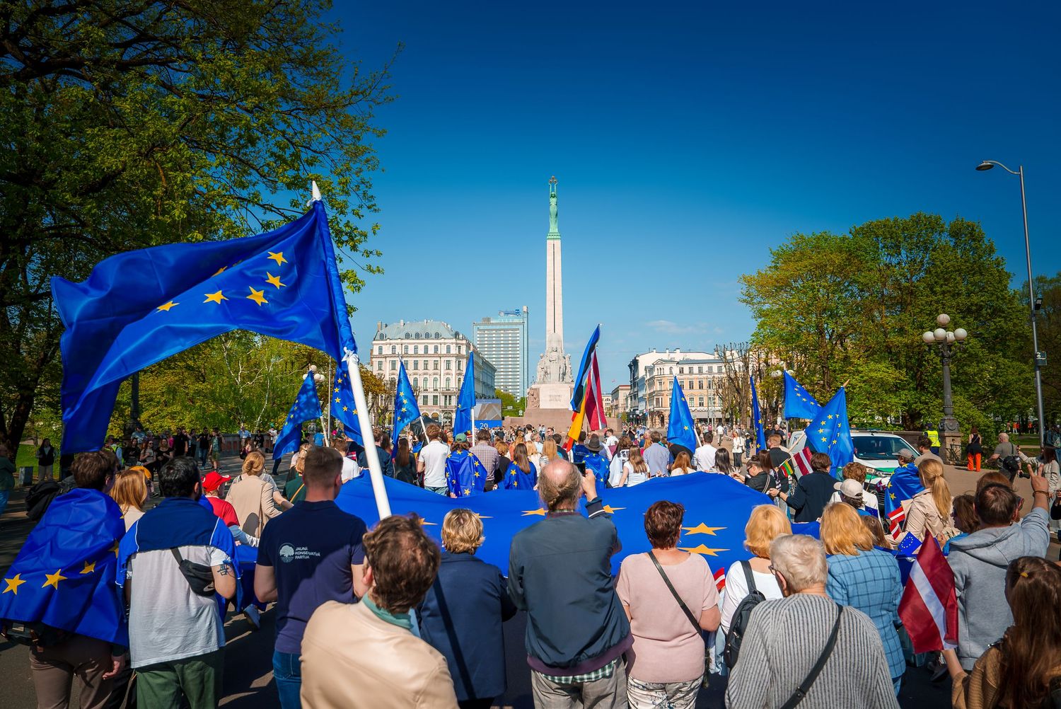 People marching with European Union flags during daytime demonstration.