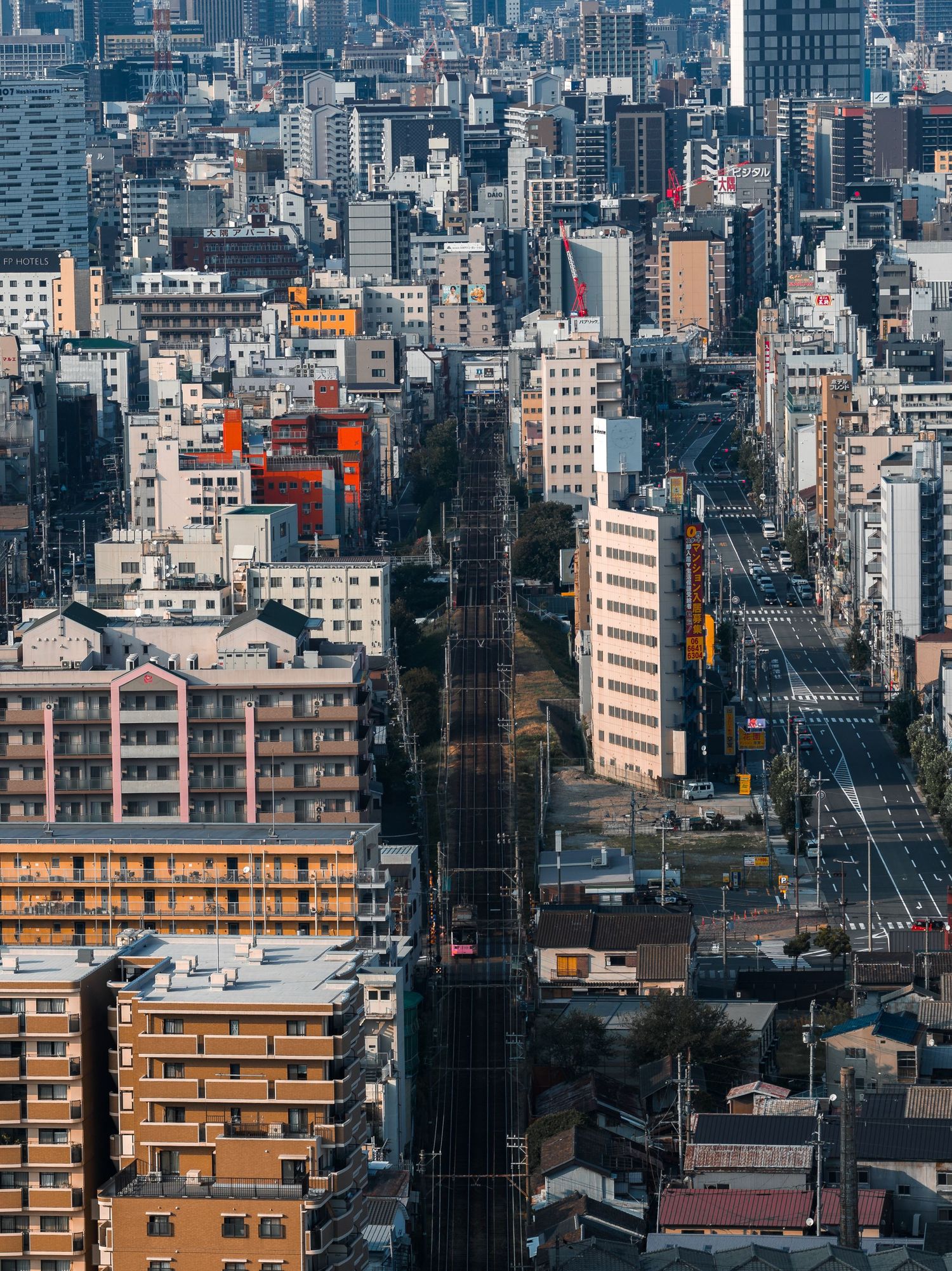 Urban cityscape showing dense residential buildings and skyscrapers in a Japanese metropolis under cloudy skies.