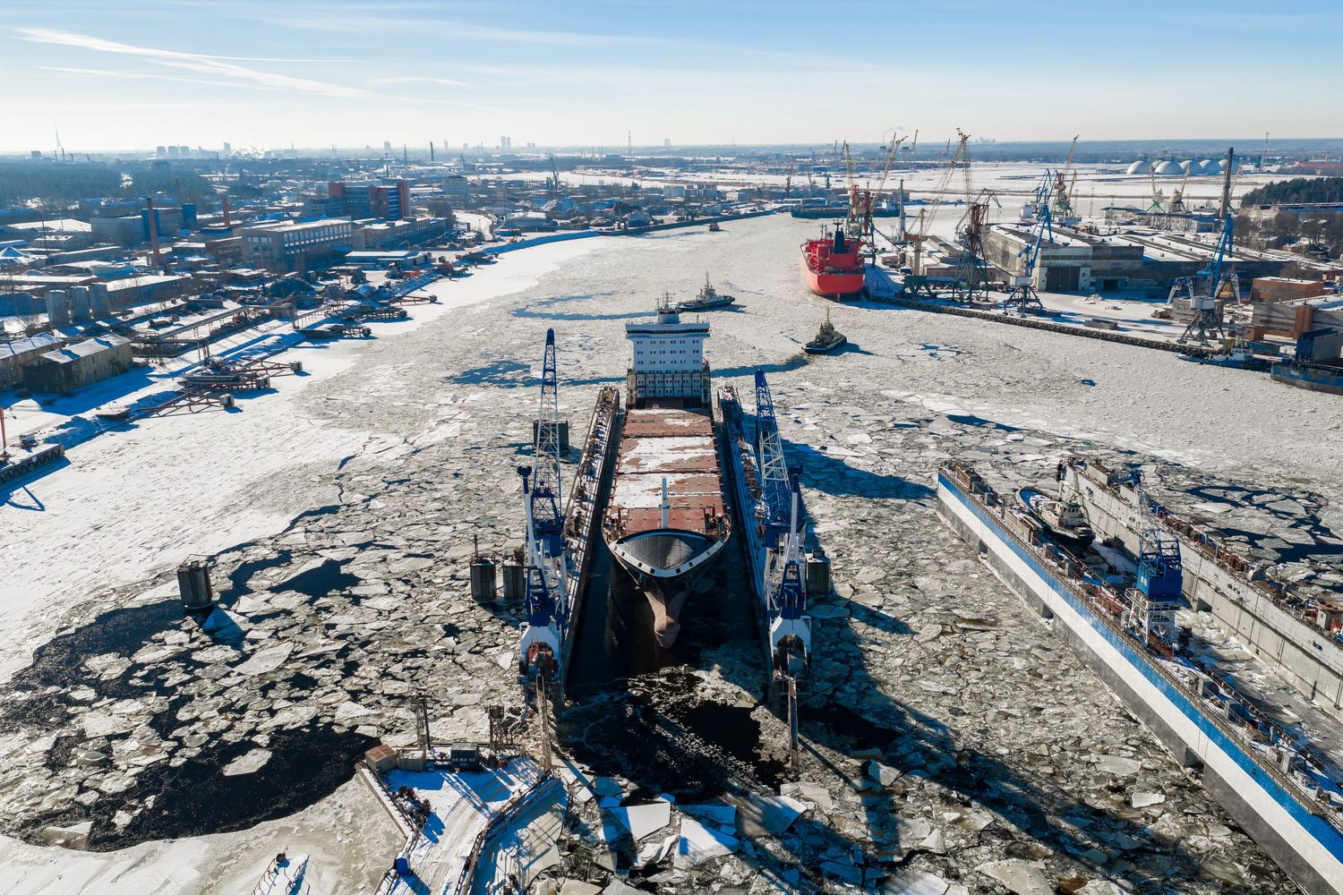 Aerial view of an industrial construction site with heavy machinery and equipment spread across snowy terrain.