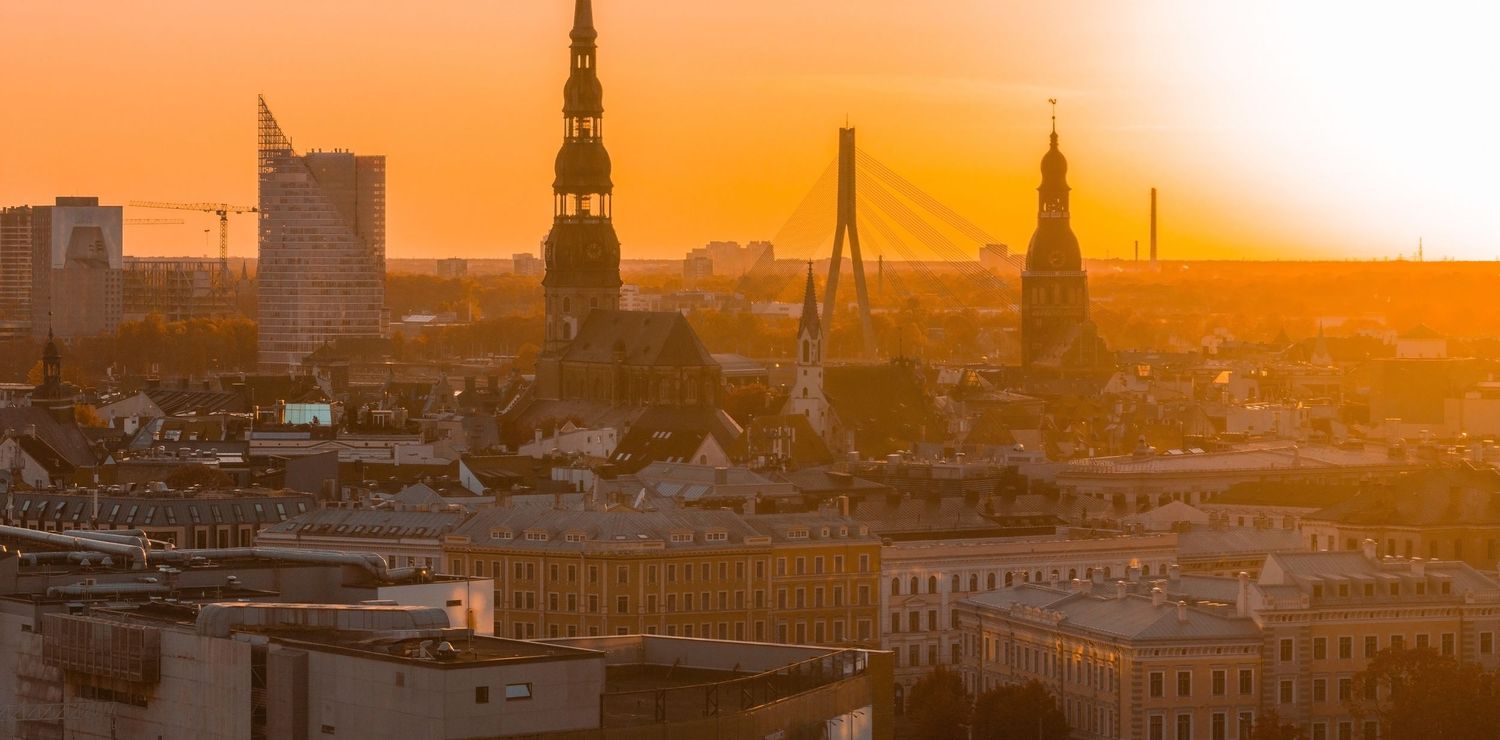 Golden sunset over London cityscape with silhouetted church spires and buildings against orange sky.