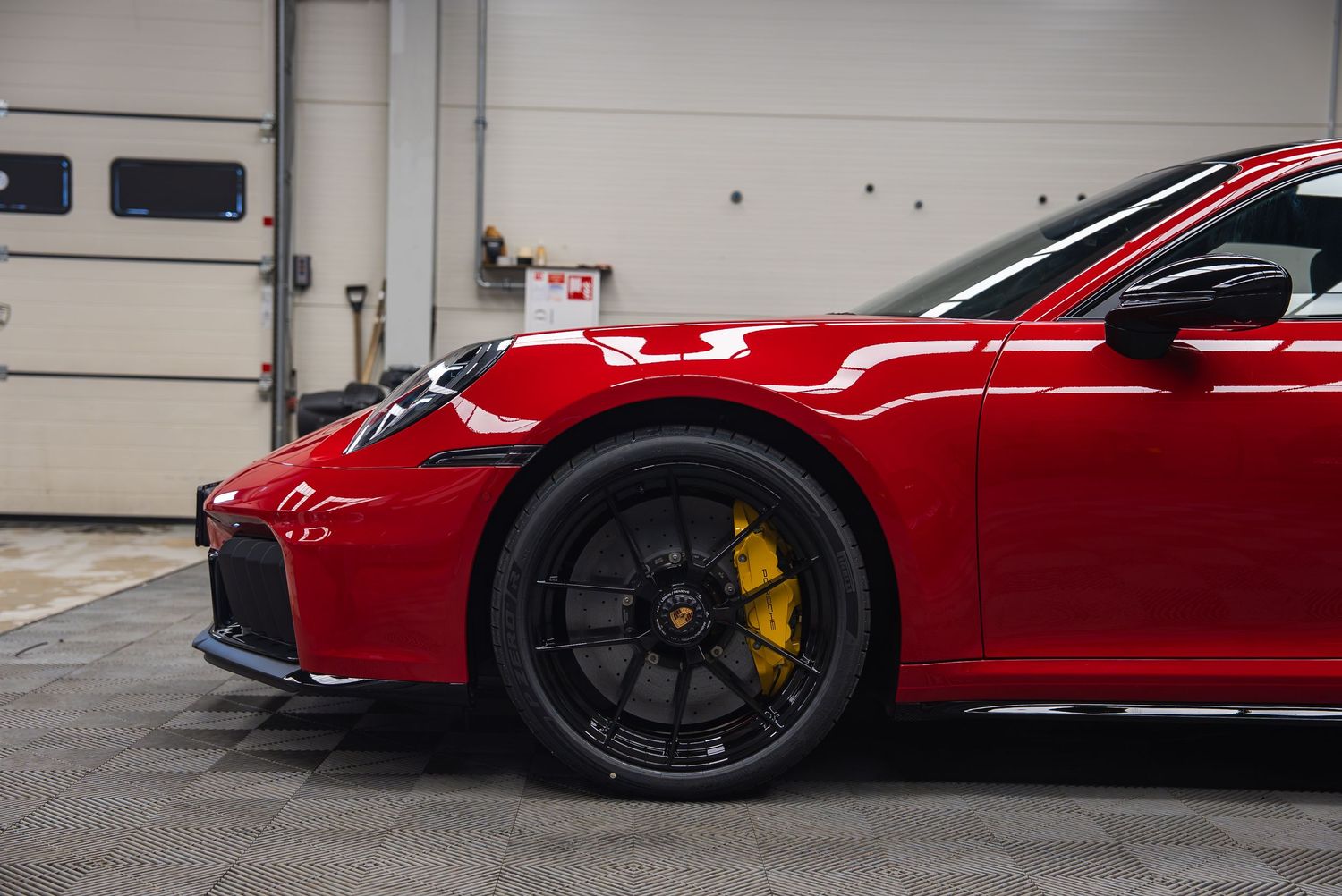 Collection of red sports cars displayed in an indoor garage with concrete floors.