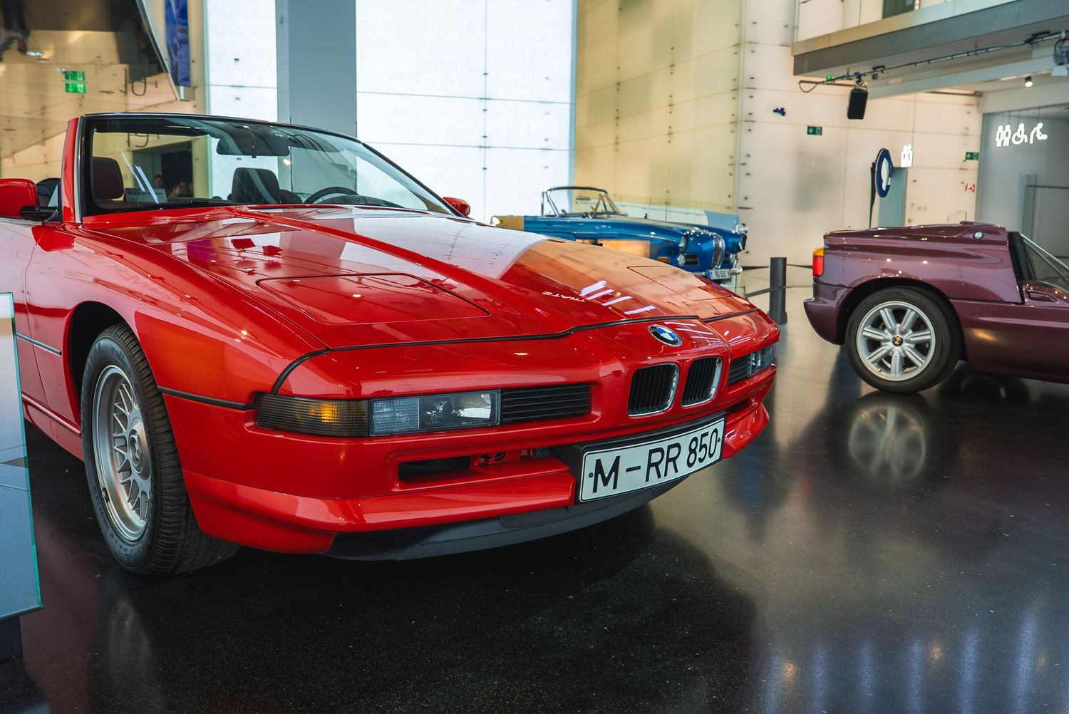 Classic red Ferrari sports cars on display in an automotive museum showroom.
