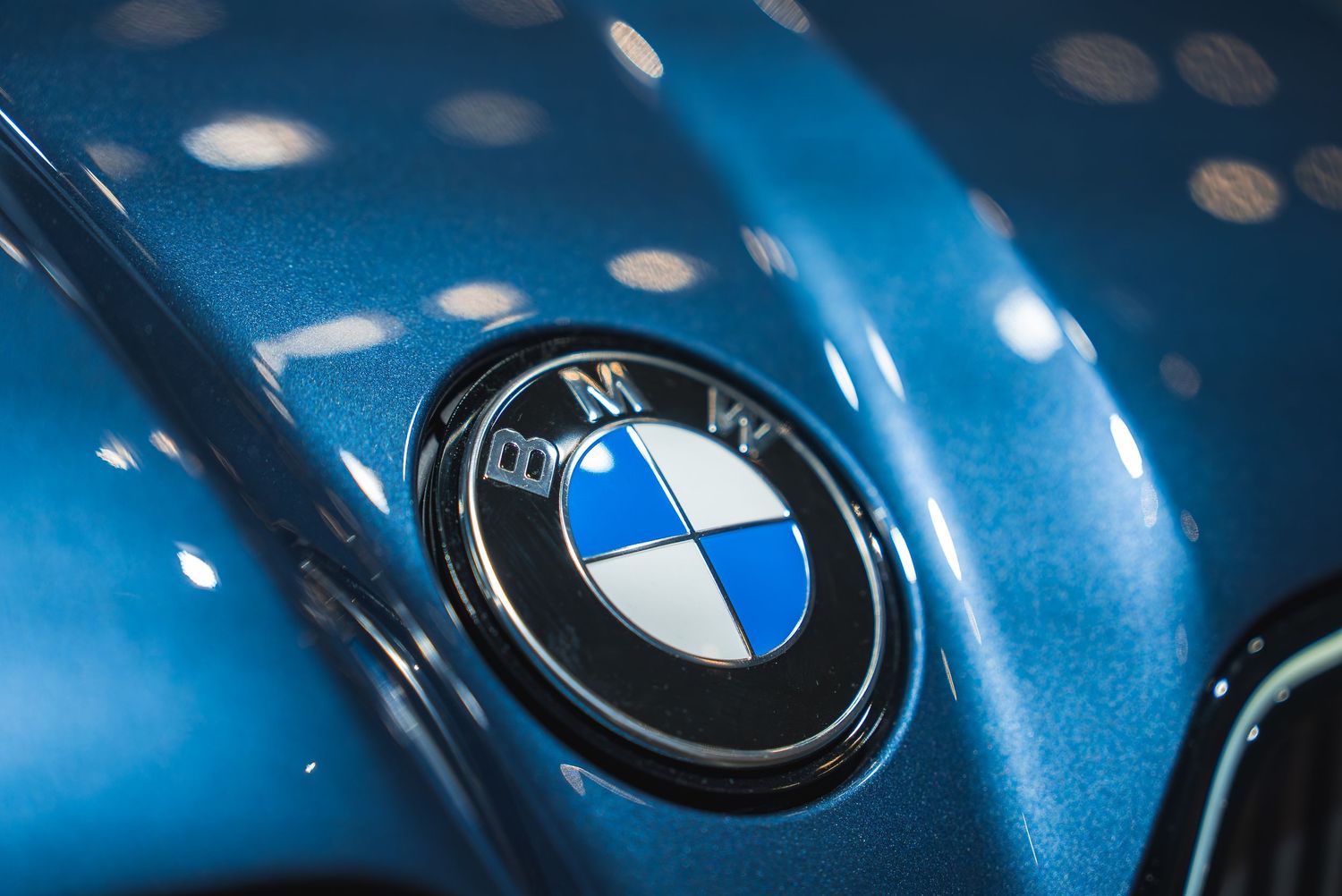 Macro shots of BMW logos and emblems on metallic blue paintwork.