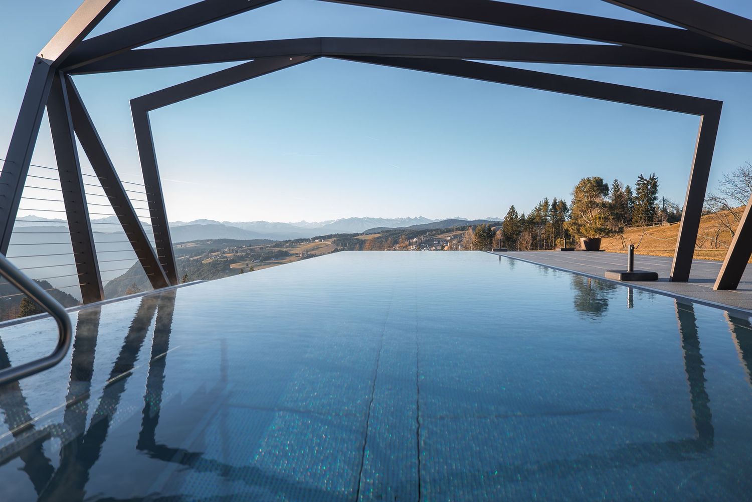 Panoramic ocean view through geometric architectural frames against a clear blue sky.
