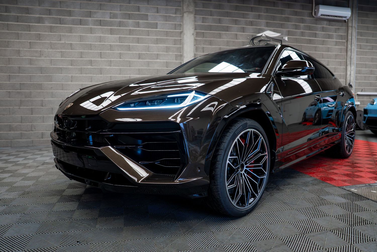 Black Lamborghini sports car displayed in industrial garage setting with dramatic lighting.