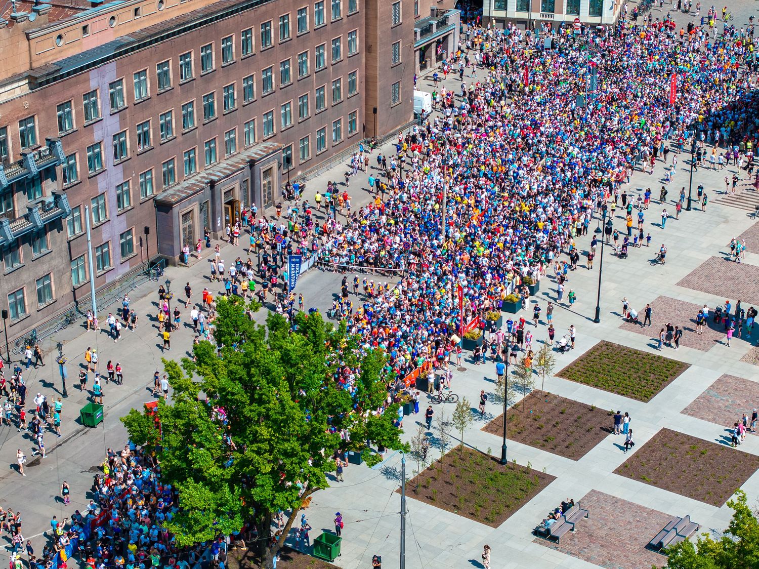 Birds-eye view of large crowd gathering outside a brick building during an event.