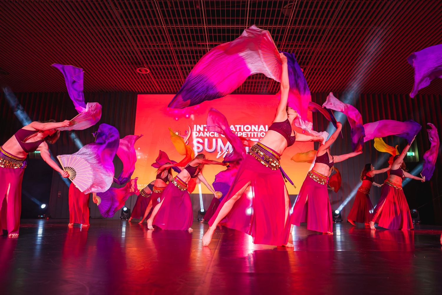 Modern dance performance with colorful lighting and flowing choreography on stage.