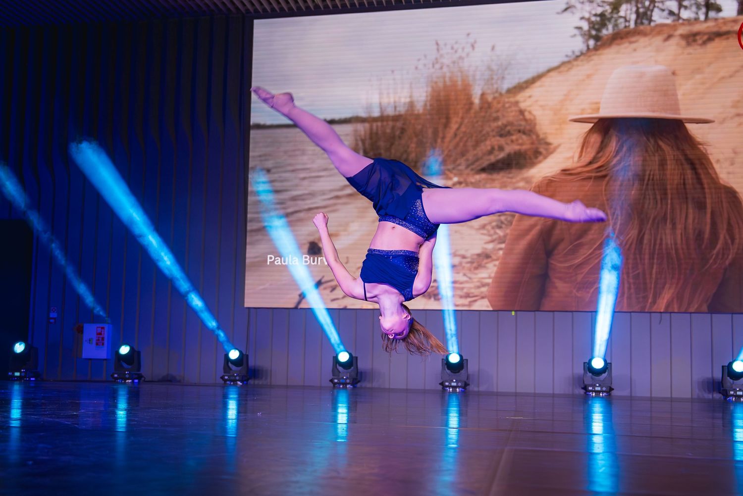 Dancers performing aerial movements with blue stage lighting creating a dramatic atmosphere.
