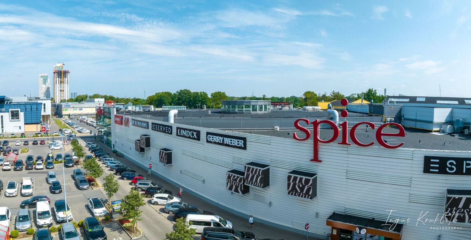 Shopping center exterior with Spice signage and busy parking lot under blue sky.