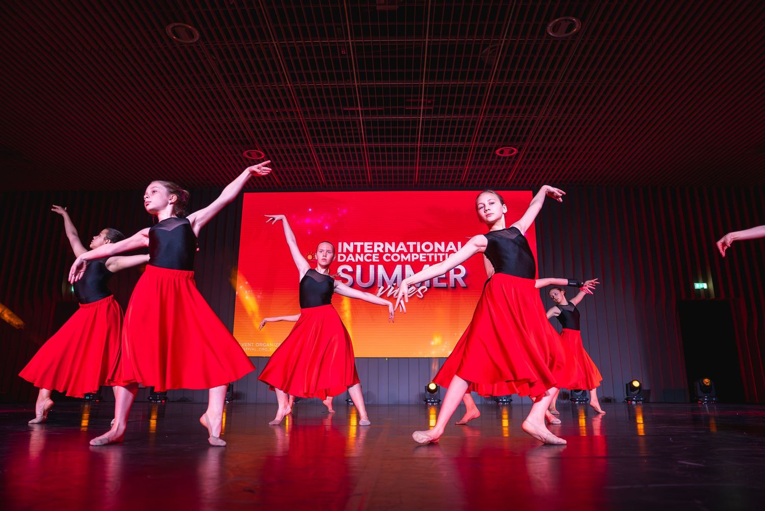 Modern dance performance featuring dancers in red costumes creating dramatic shapes on stage.