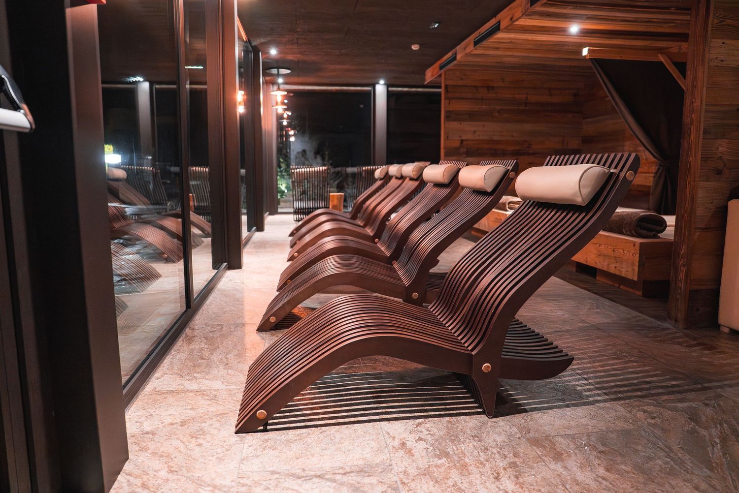 Spa relaxation room featuring ergonomic wooden loungers with warm ambient lighting.