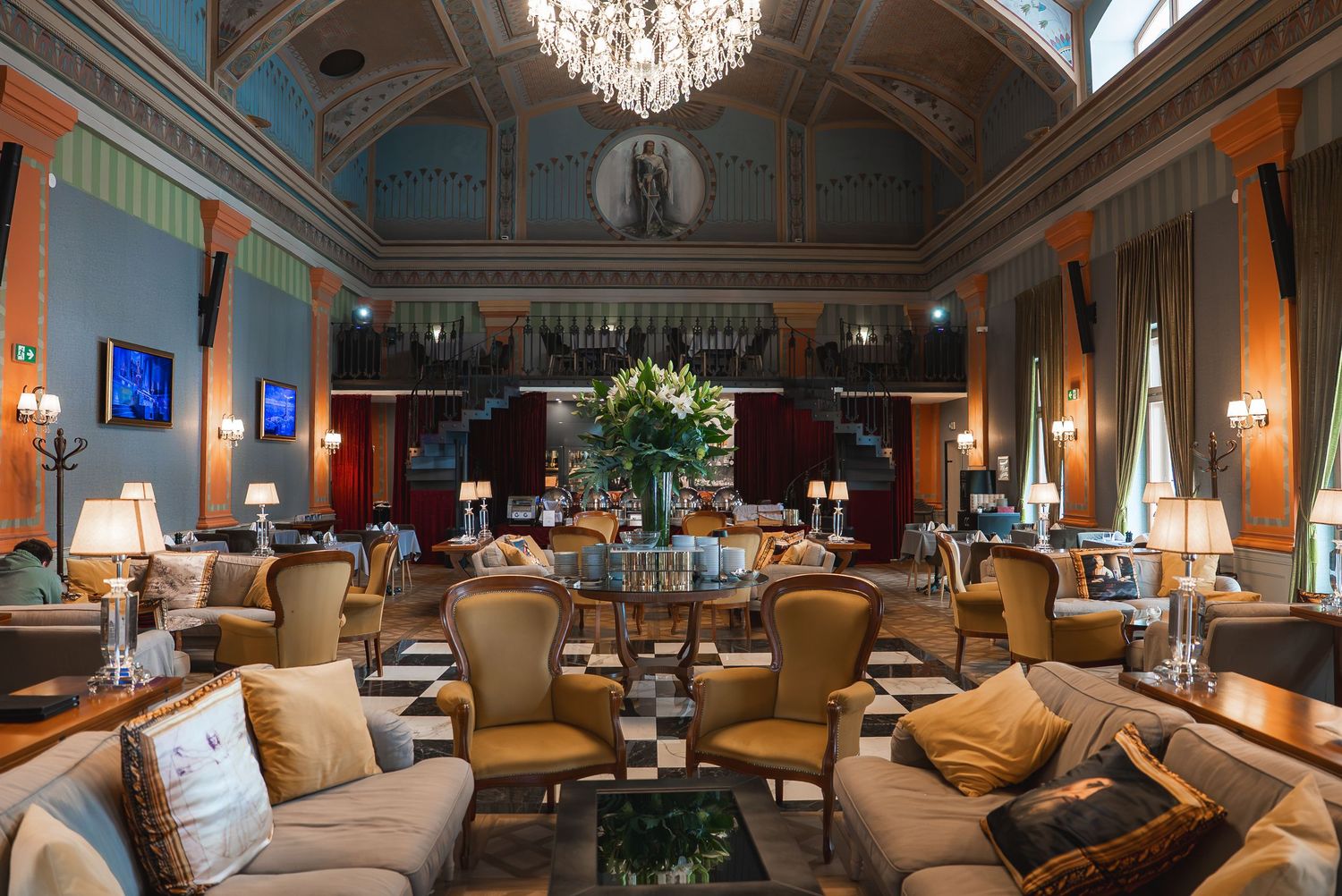 Luxurious dining hall with vaulted ceiling, crystal chandeliers, and comfortable seating arrangements.