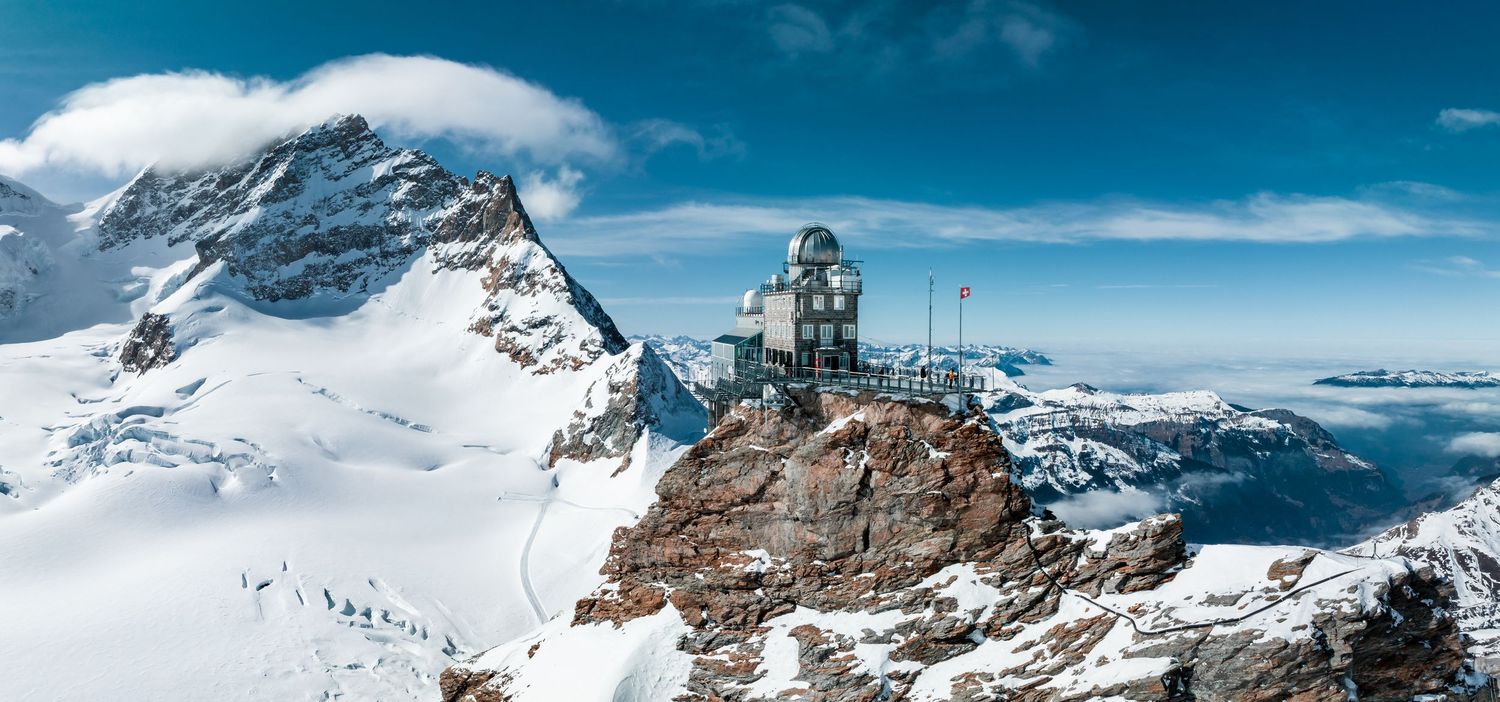 Panoramic winter mountain landscape with snow-covered peaks and blue sky.
