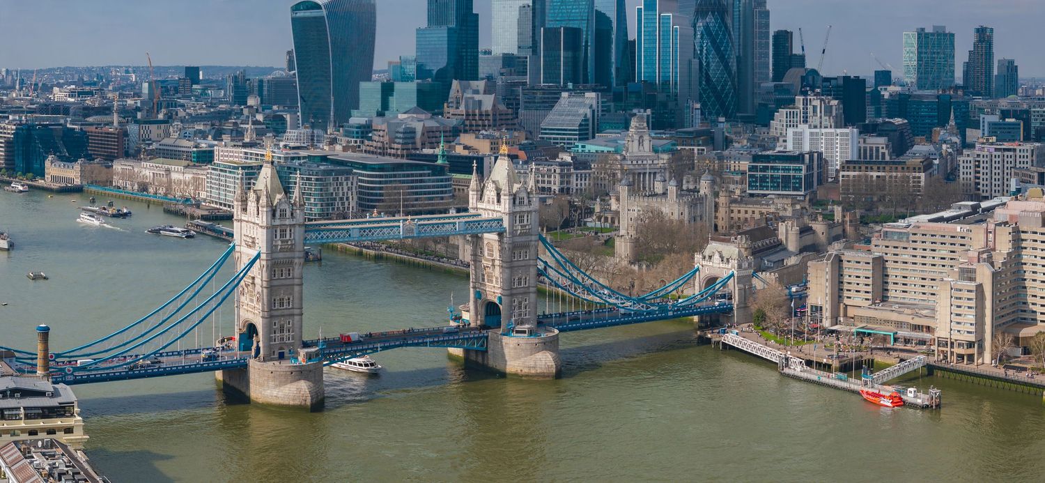 Tower Bridge spans the River Thames with London's modern financial district skyline in the background.