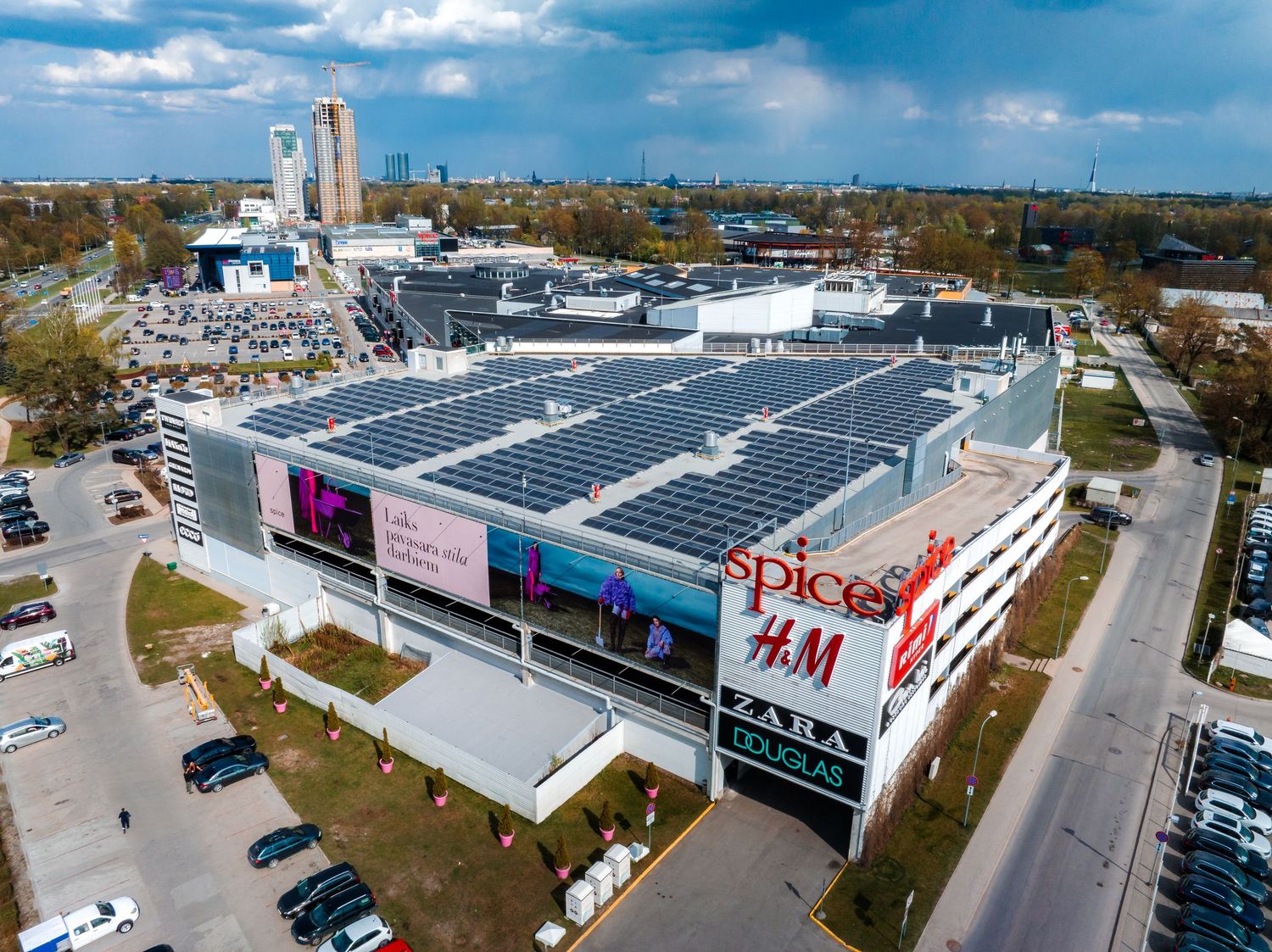 Aerial view of a shopping mall with H&M store and solar panels on the roof.