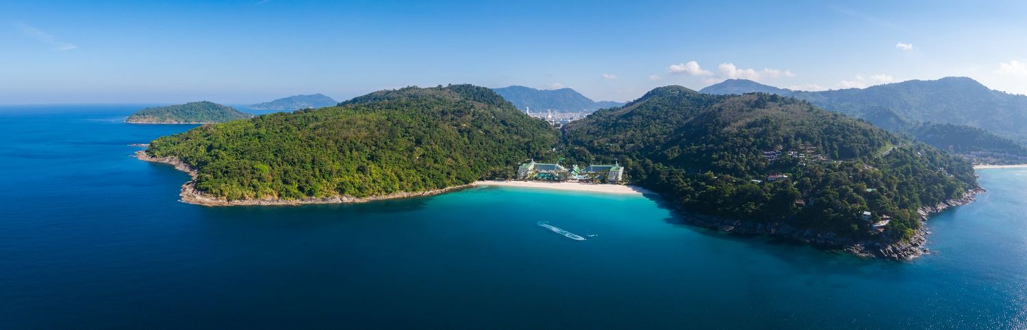 Aerial panorama of tropical coastline with mountains, forests and turquoise waters.