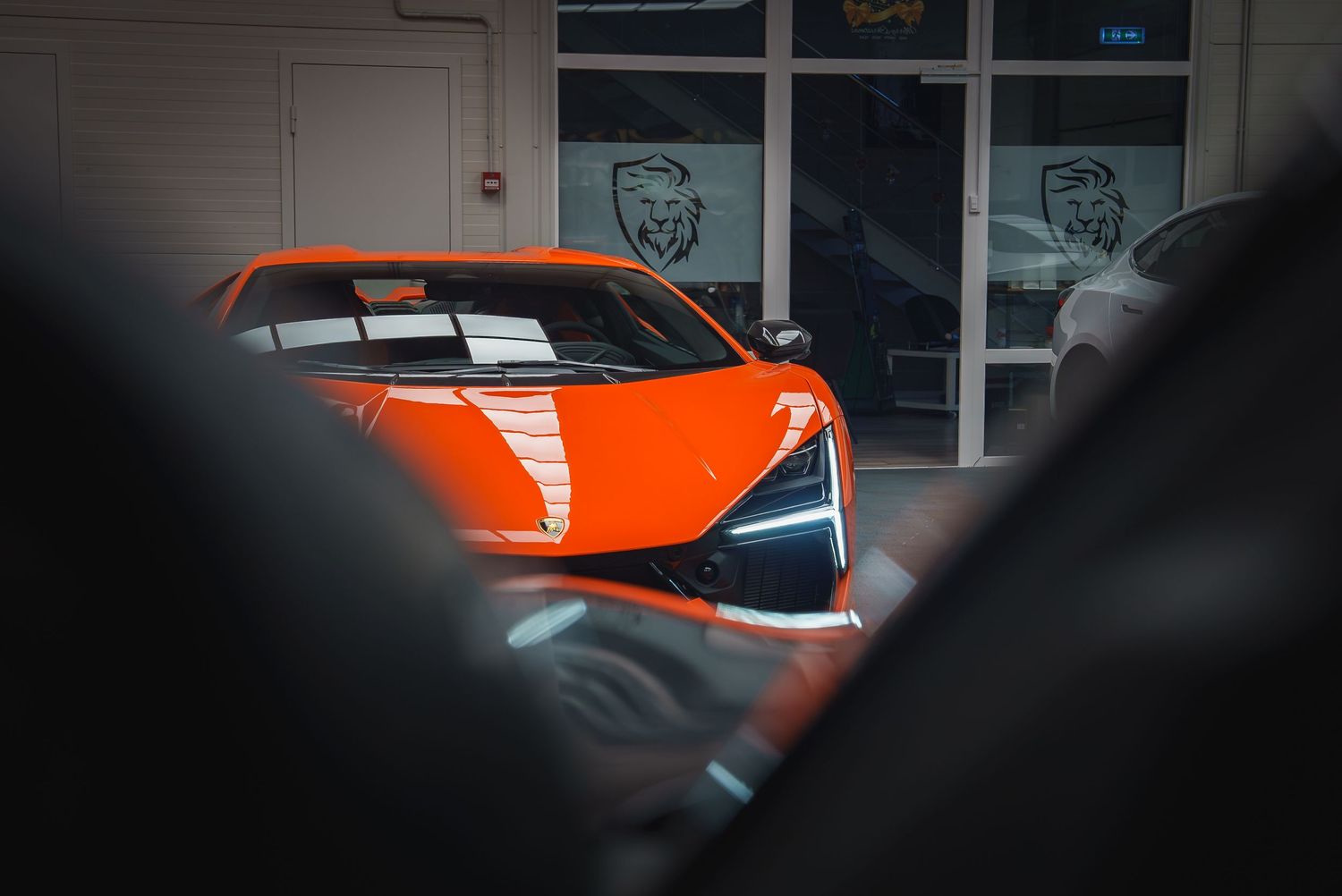 Orange supercar parked in front of a building in low light conditions.