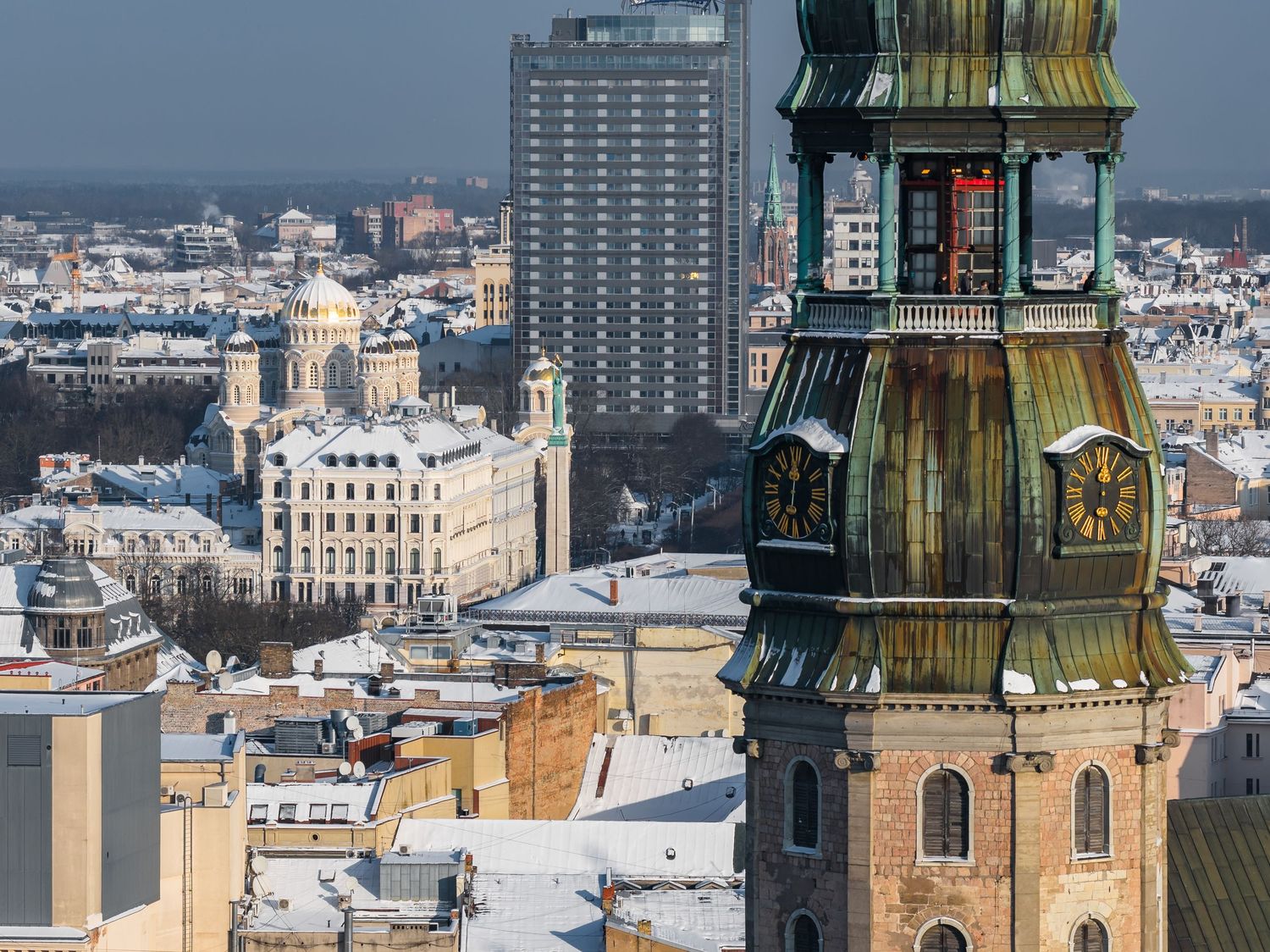 Aerial panoramic view of historic Prague cityscape with ornate church spires and traditional architecture on a sunny day.