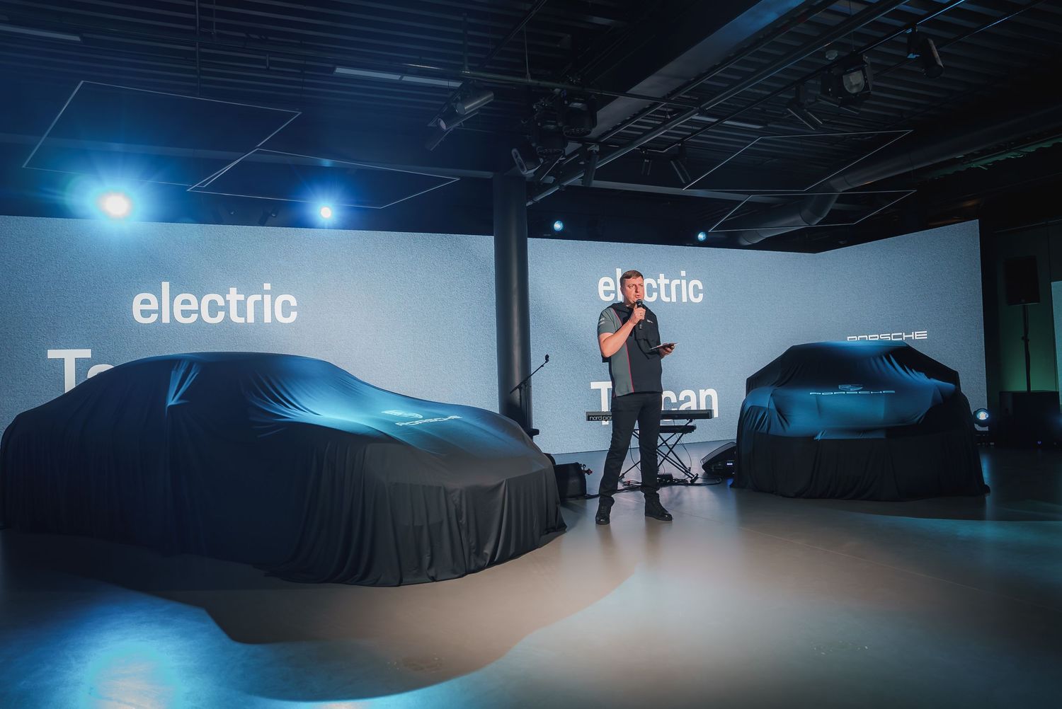 Wide interior shot of a dimly lit automotive showroom with dramatic blue lighting.