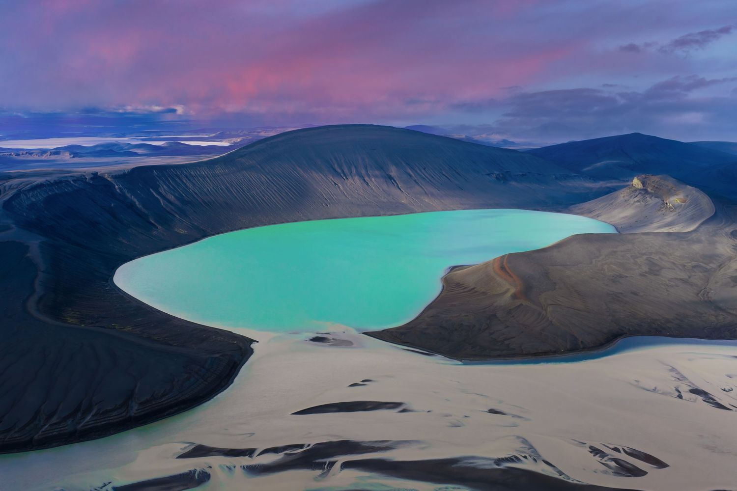 Aerial views of a turquoise volcanic crater lake in Iceland surrounded by rugged mountains at different angles and times of day.
